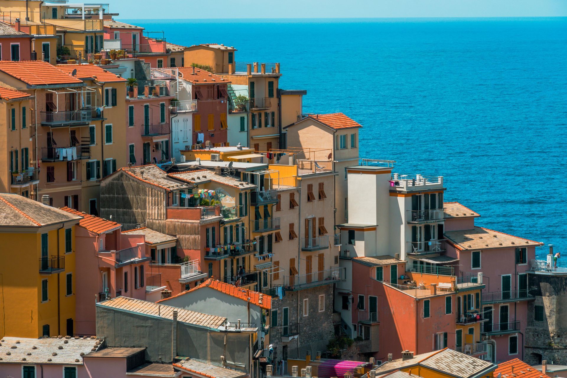 A group of buildings sitting on top of a hill next to the ocean in Cinque Terre, Italy.