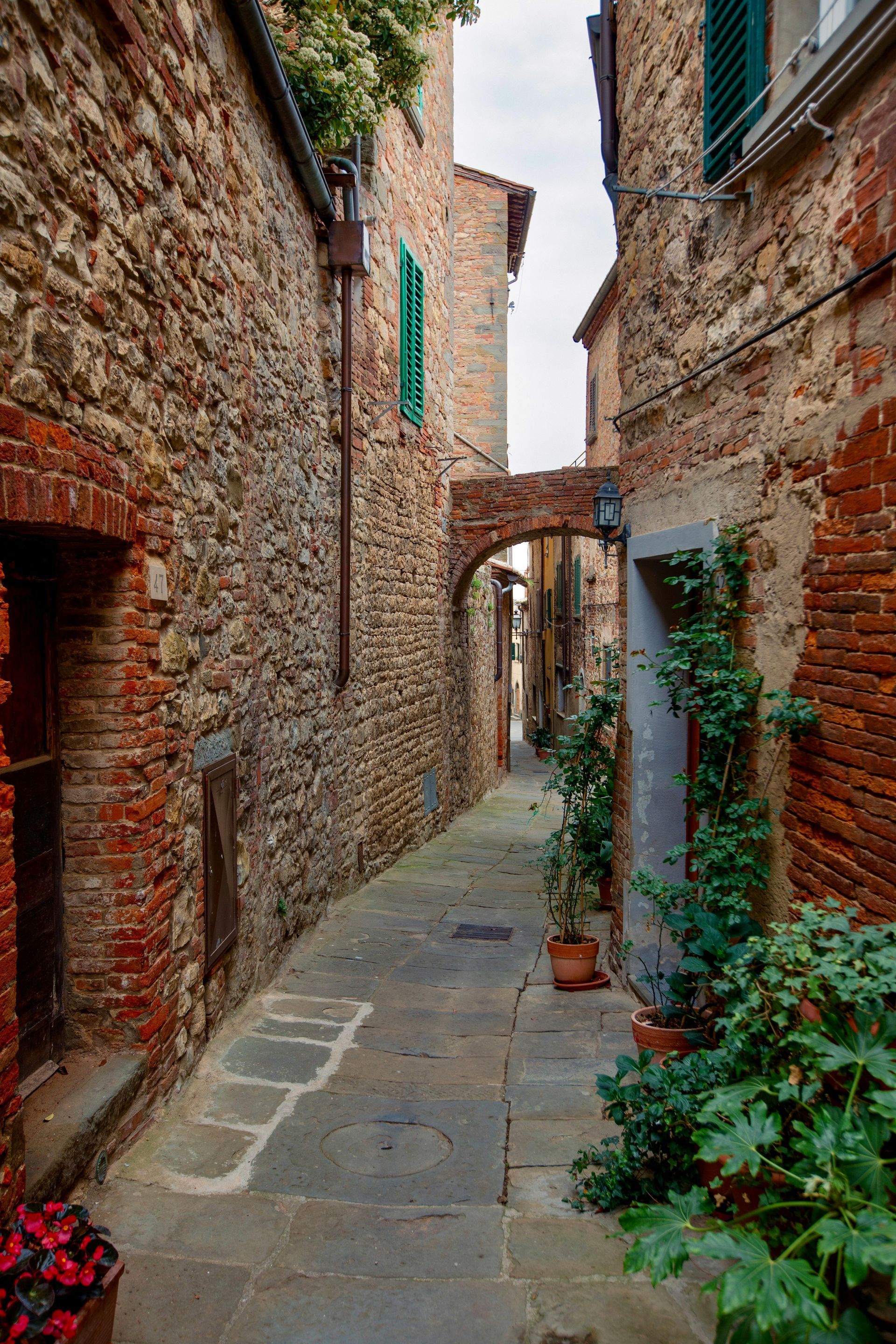 A narrow alleyway between two brick buildings in a small town in Tuscany, Italy.