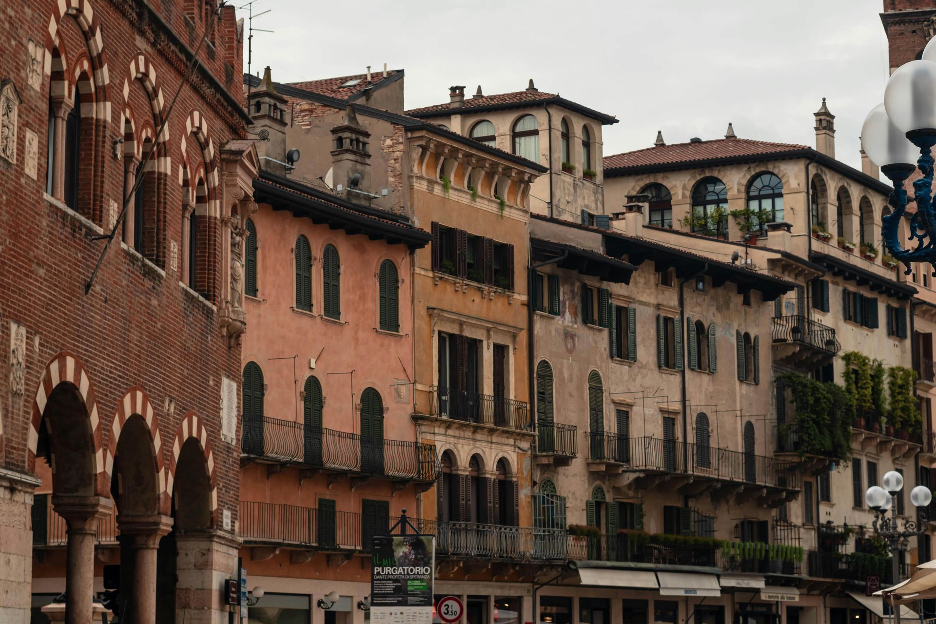 A row of buildings with arches and balconies in a city in Verona, Italy.