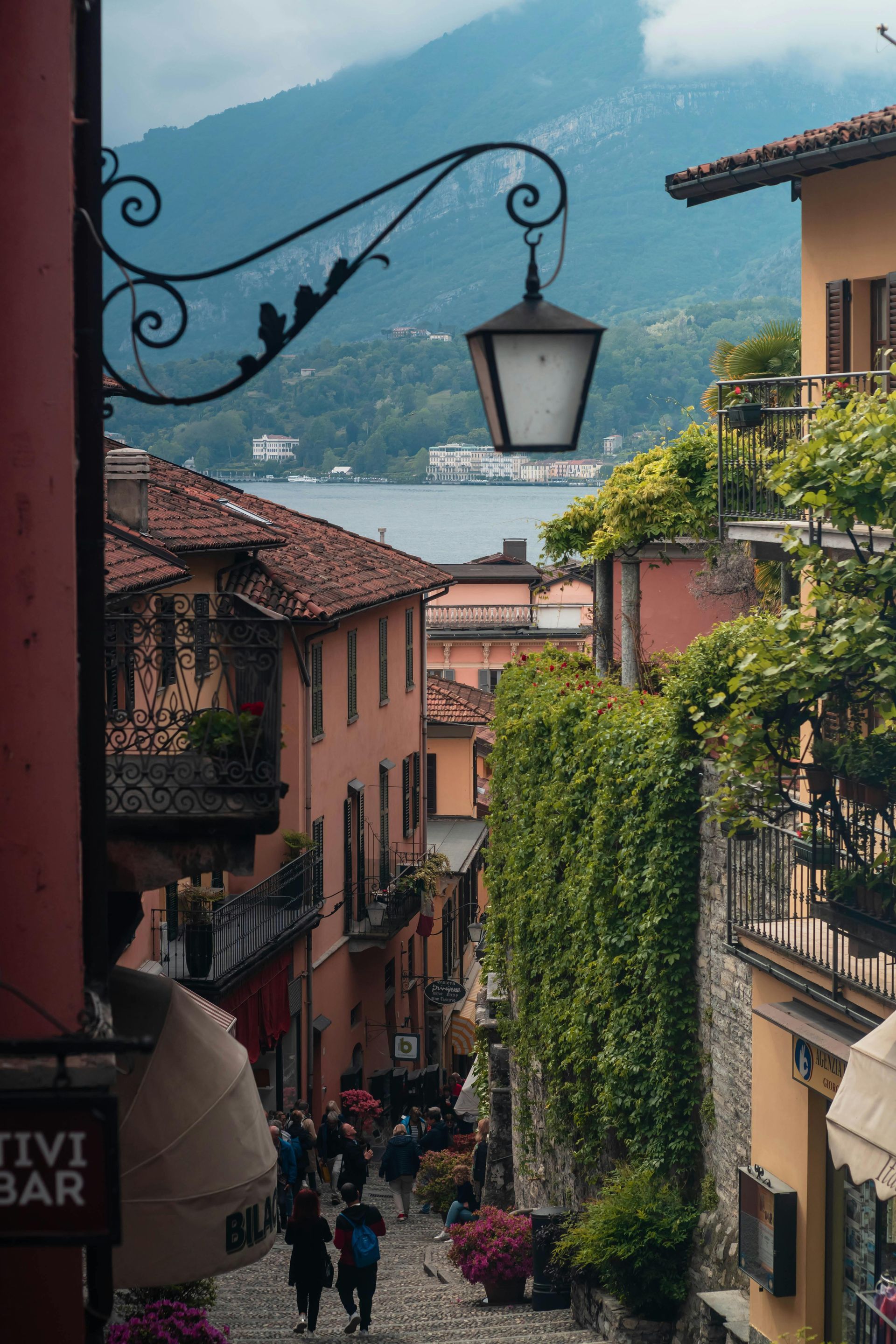 A group of people are walking down a cobblestone street in a small town on Lake Como in Italy.