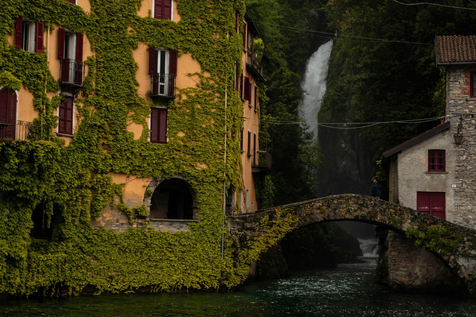 There is a waterfall in the background and a bridge in the foreground on lake como in Italy,