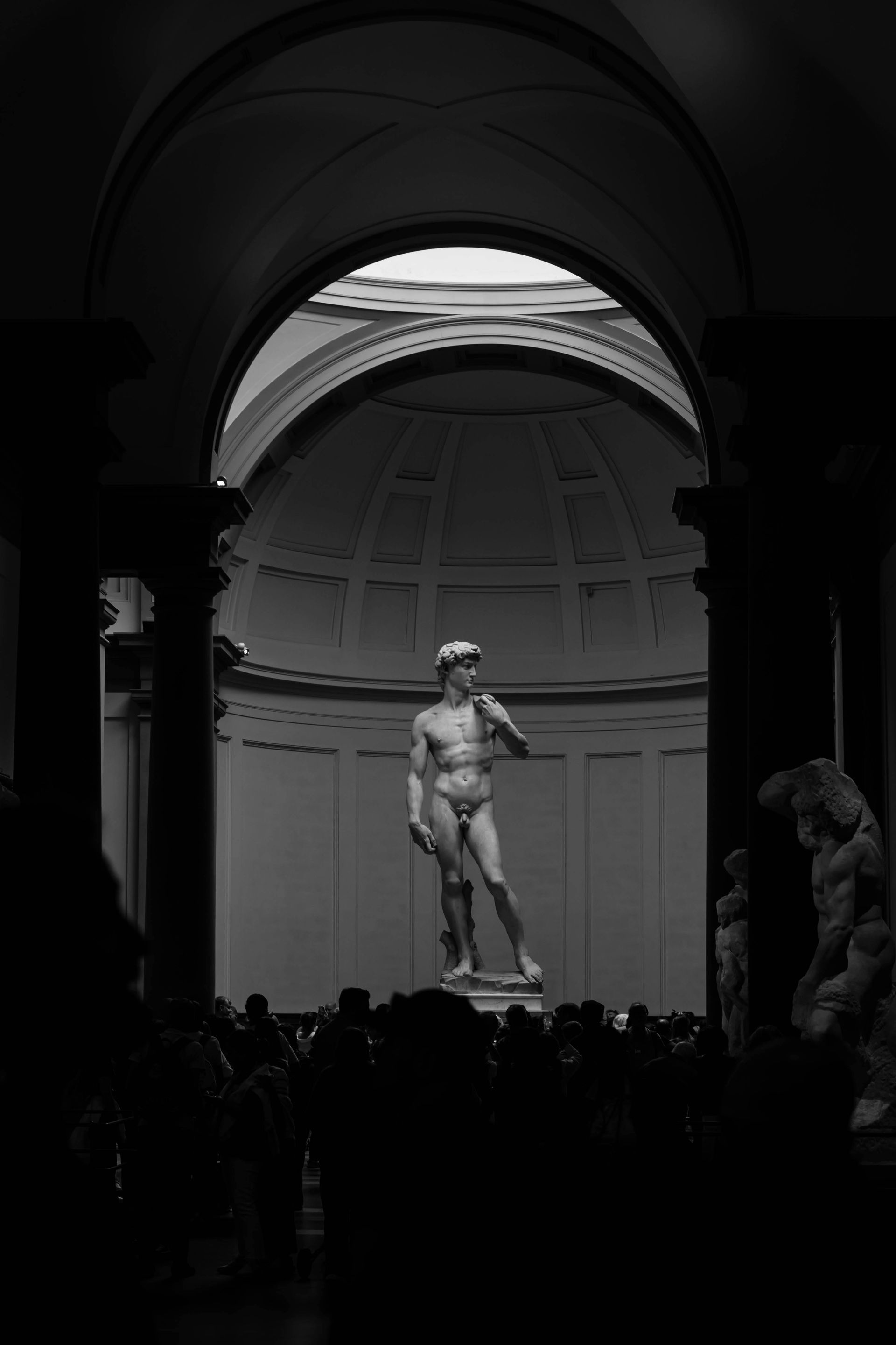 A black and white photo of a statue of a man in a building in Florence, Italy.