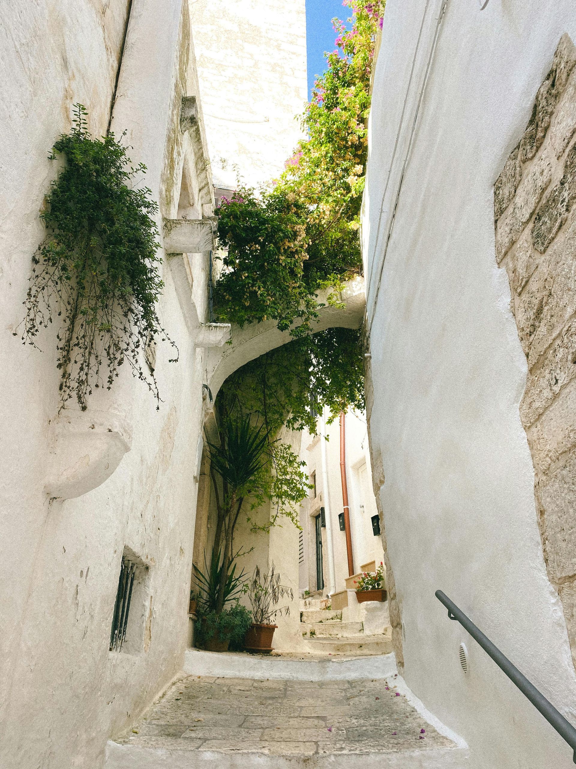 A narrow alleyway of Ostuni between two white buildings in Puglia, Italy.