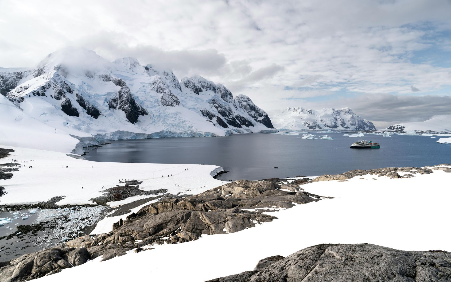 A large body of water surrounded by snow covered mountains  in Antarctica.