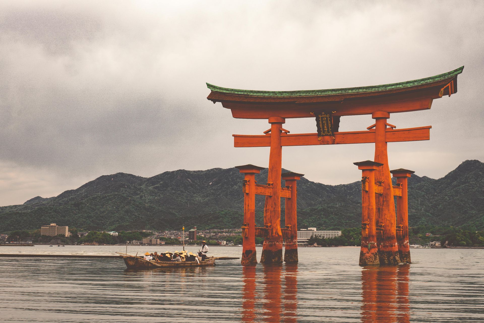 A torii gate in the middle of a lake with mountains in the background at the  Itsukushima Shrine in Japan.