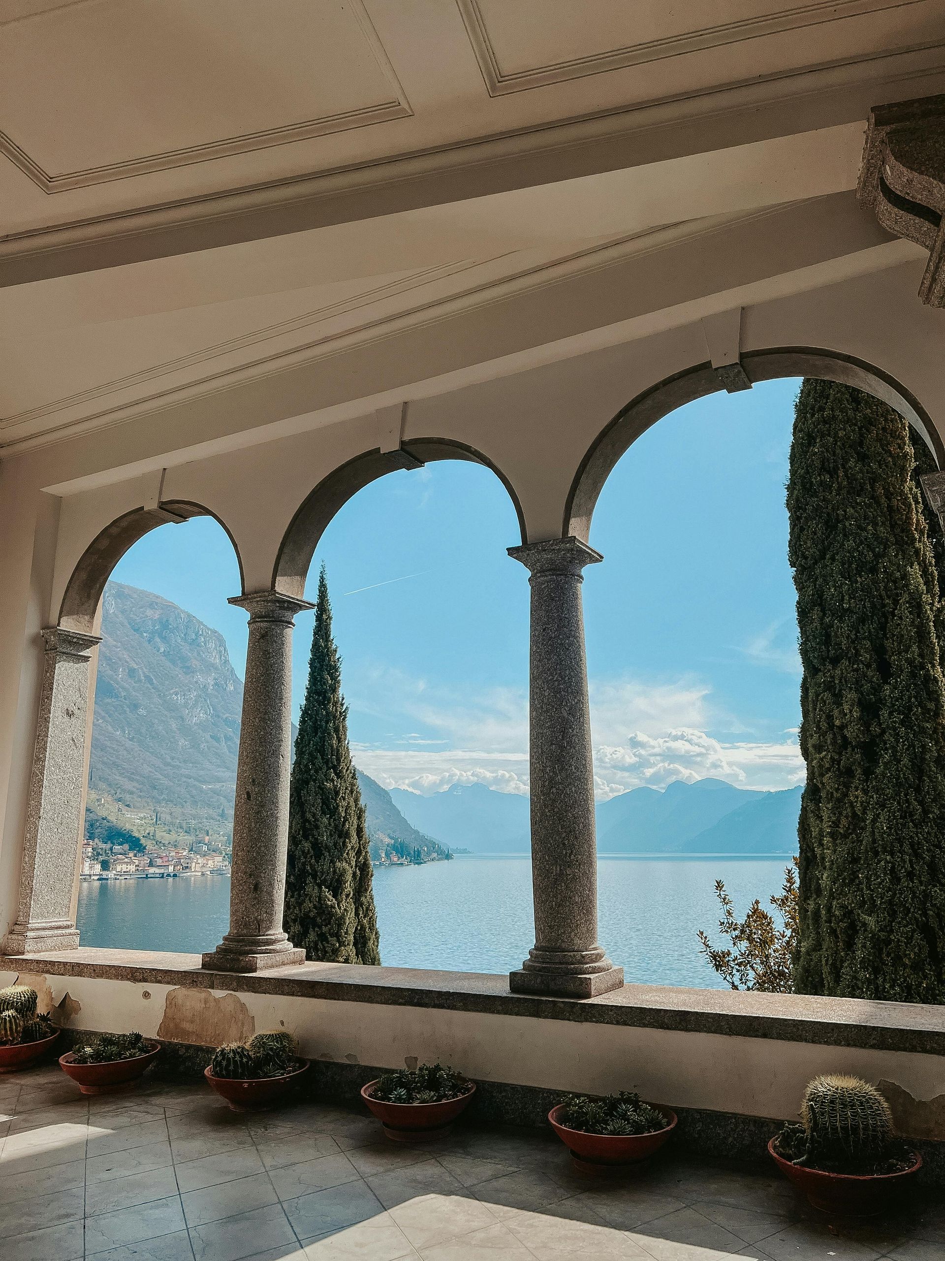 A balcony with arches overlooking a lake and mountains on Lake Como, Italy.