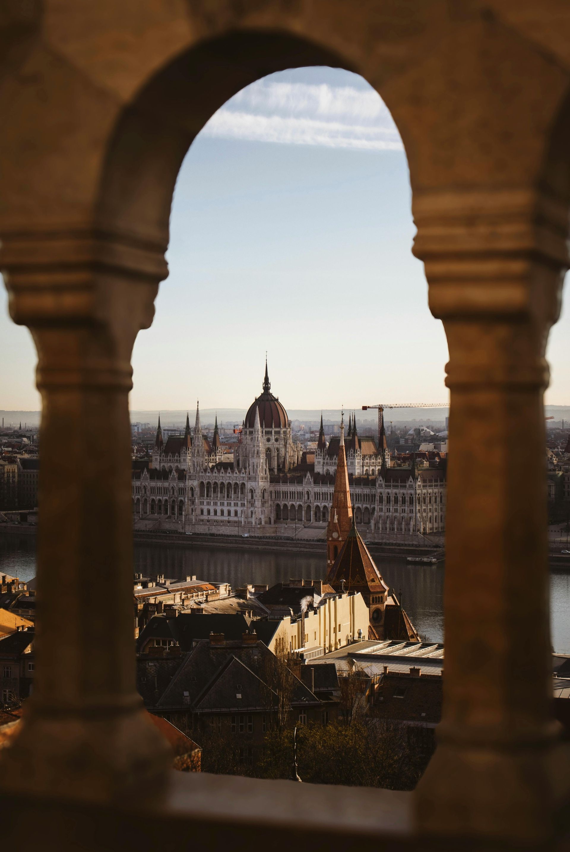 A view of Budapest, Hungary, and the Hungarian Parliament Building through a stone archway.