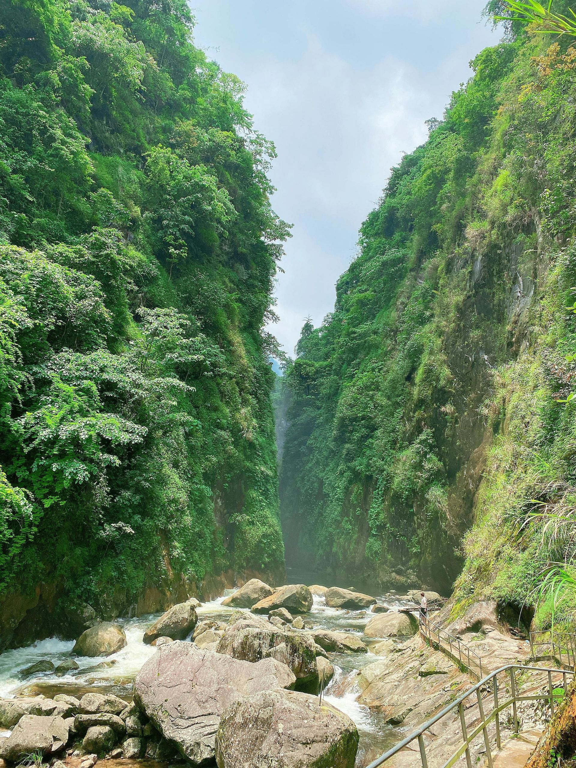 There is a waterfall in the middle of a canyon surrounded by trees in Laos.