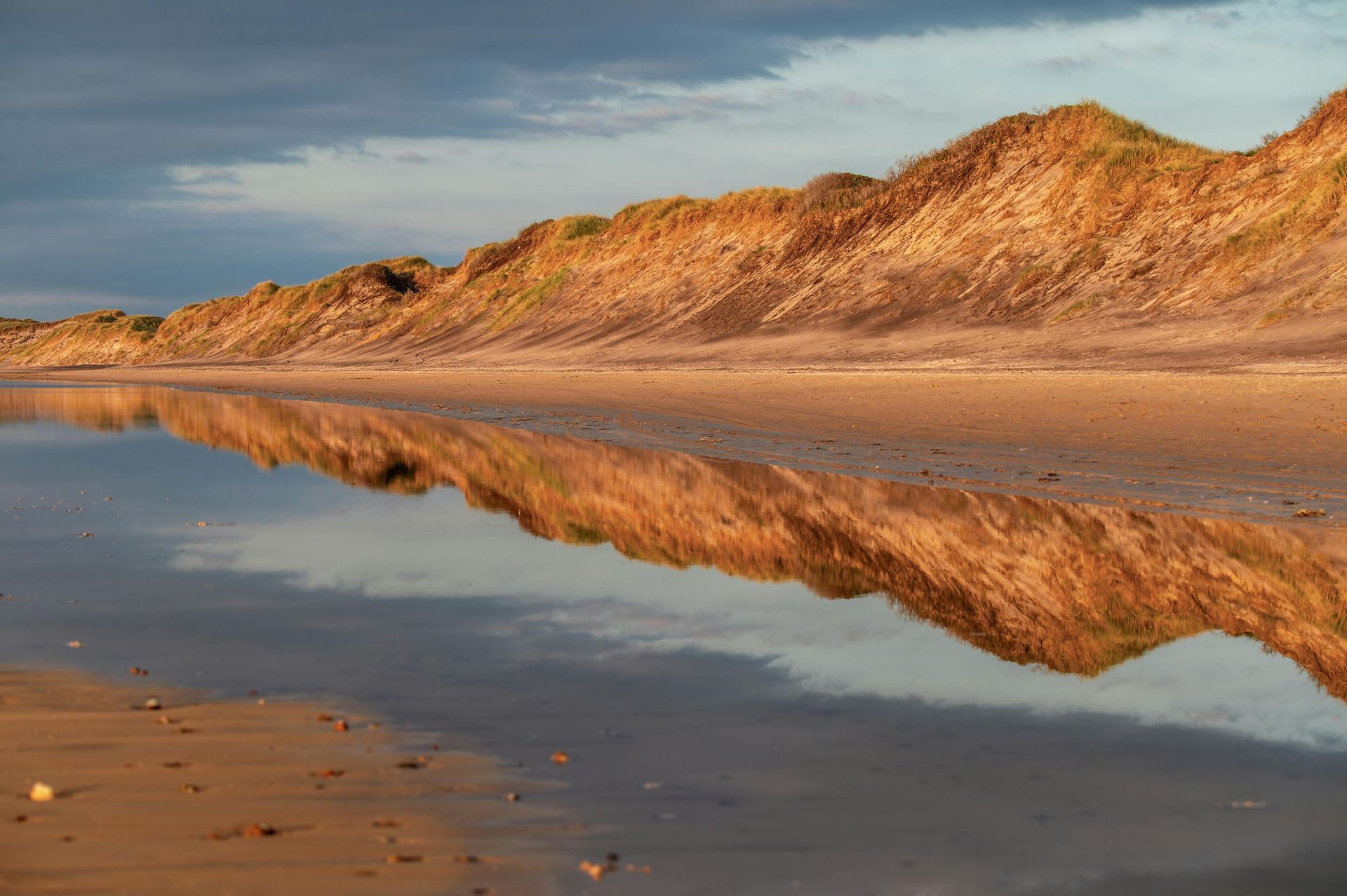 There is a reflection of a mountain in the water on the beach in Denmark.