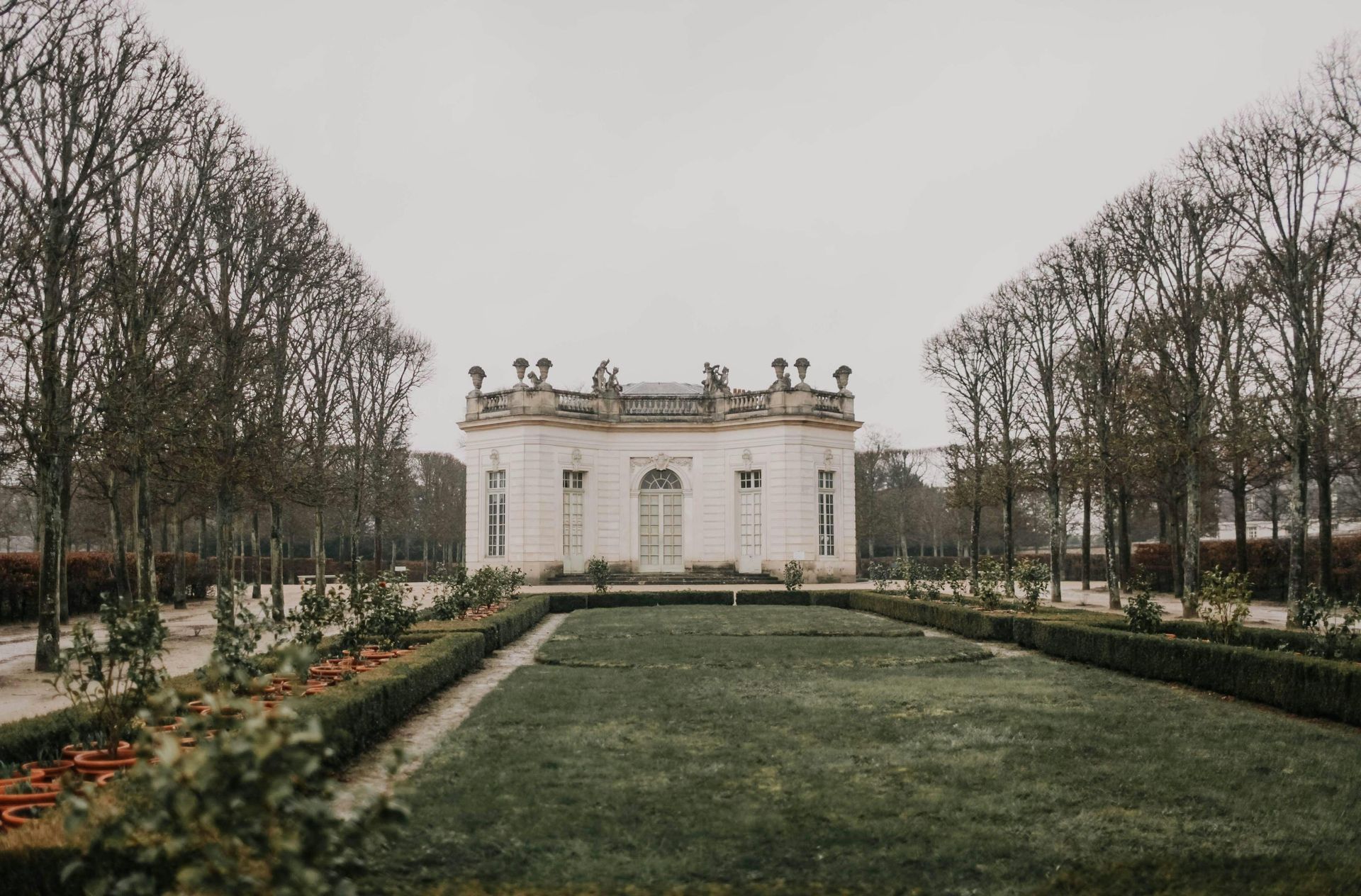 There is a large white building in the middle of a park surrounded by trees in northern France. 