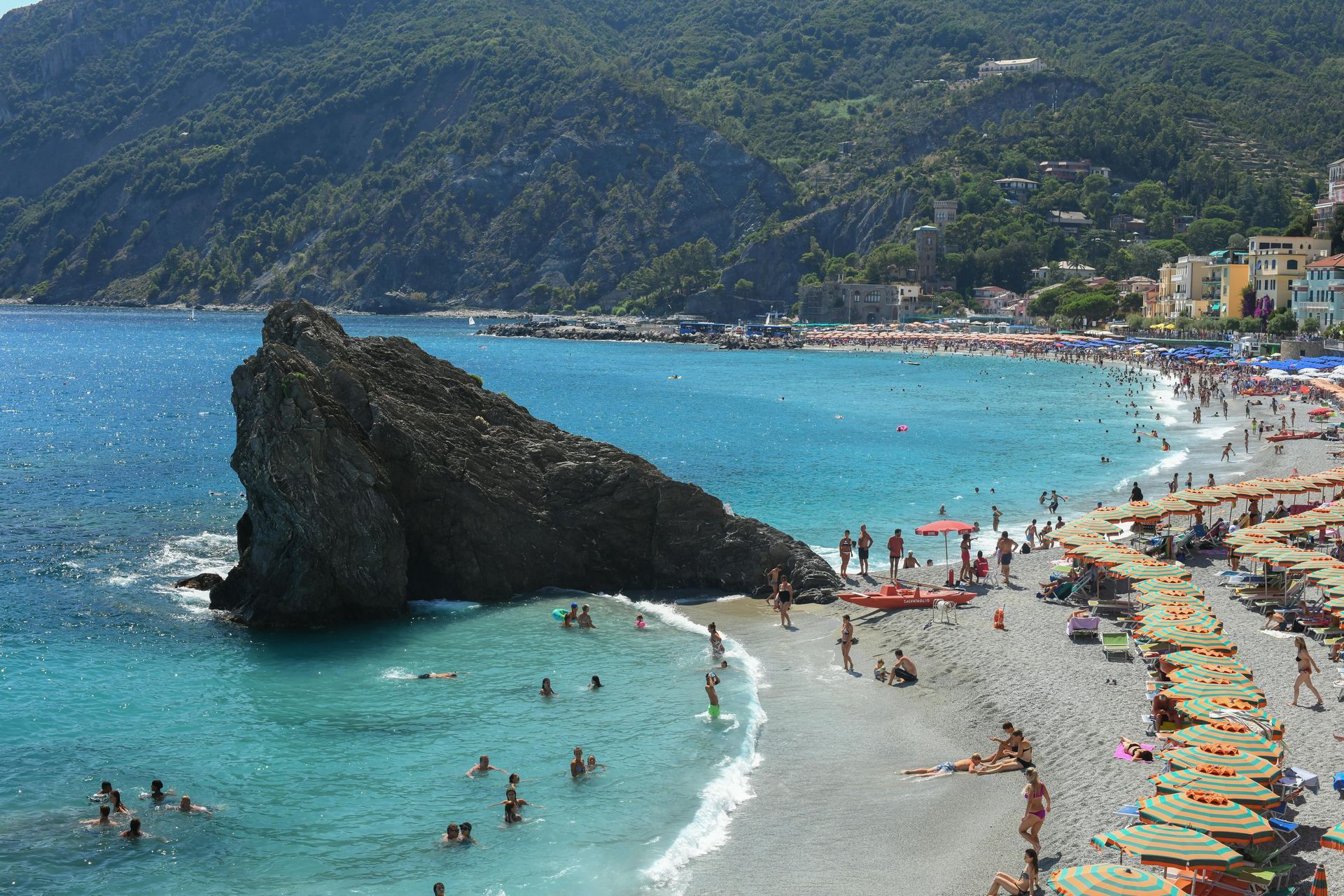 A beach with a large rock in the middle of it in Cinque Terre, Italy.