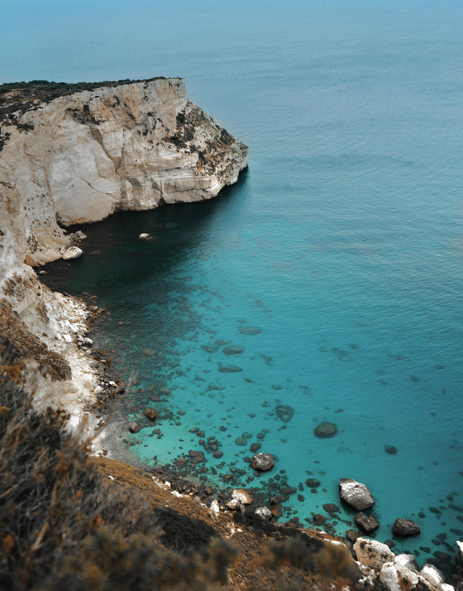 A large body of water with a cliff in the background in Sardinia, Italy.