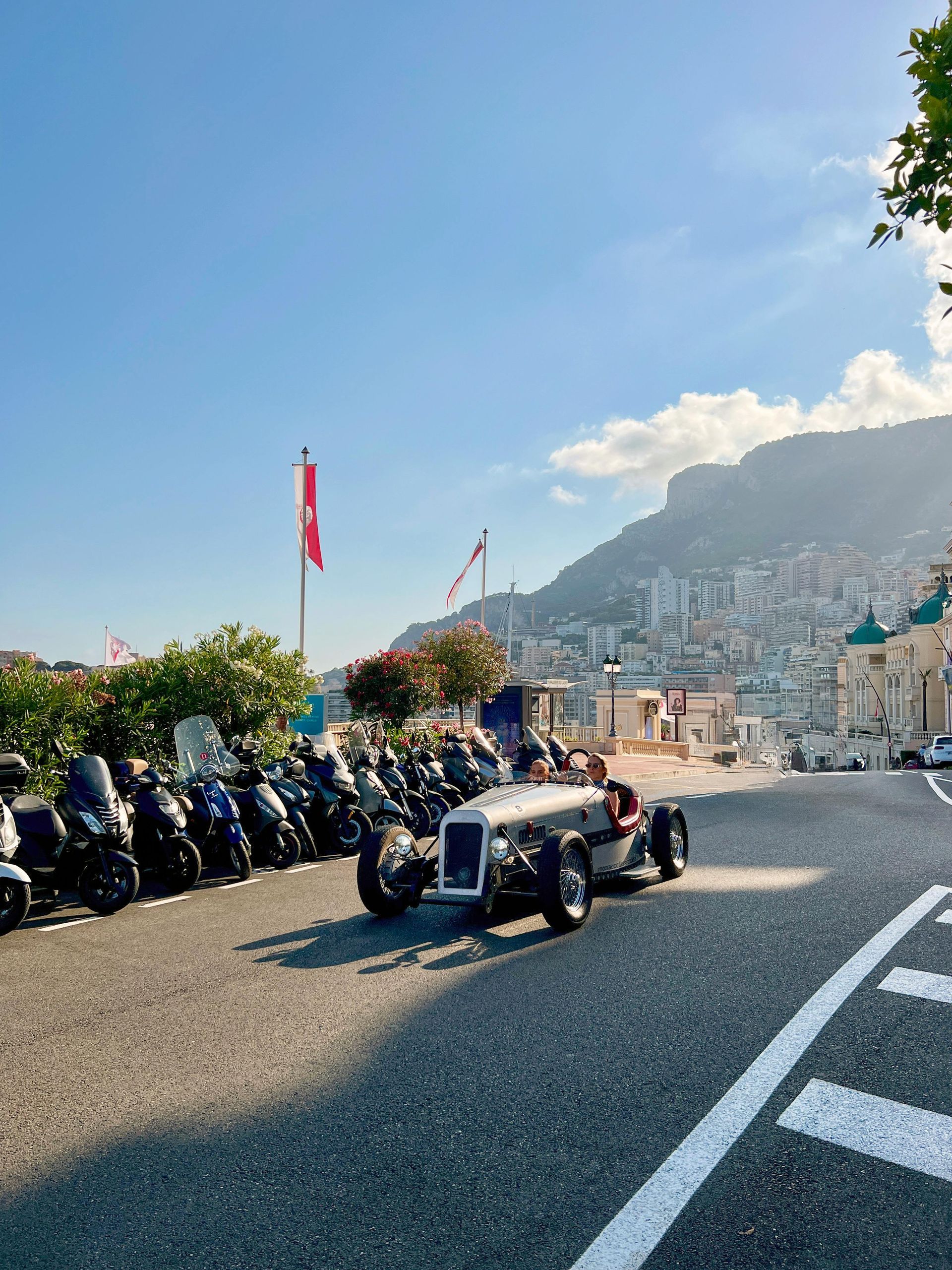 A row of motorcycles are parked on the side of the road in Monaco.