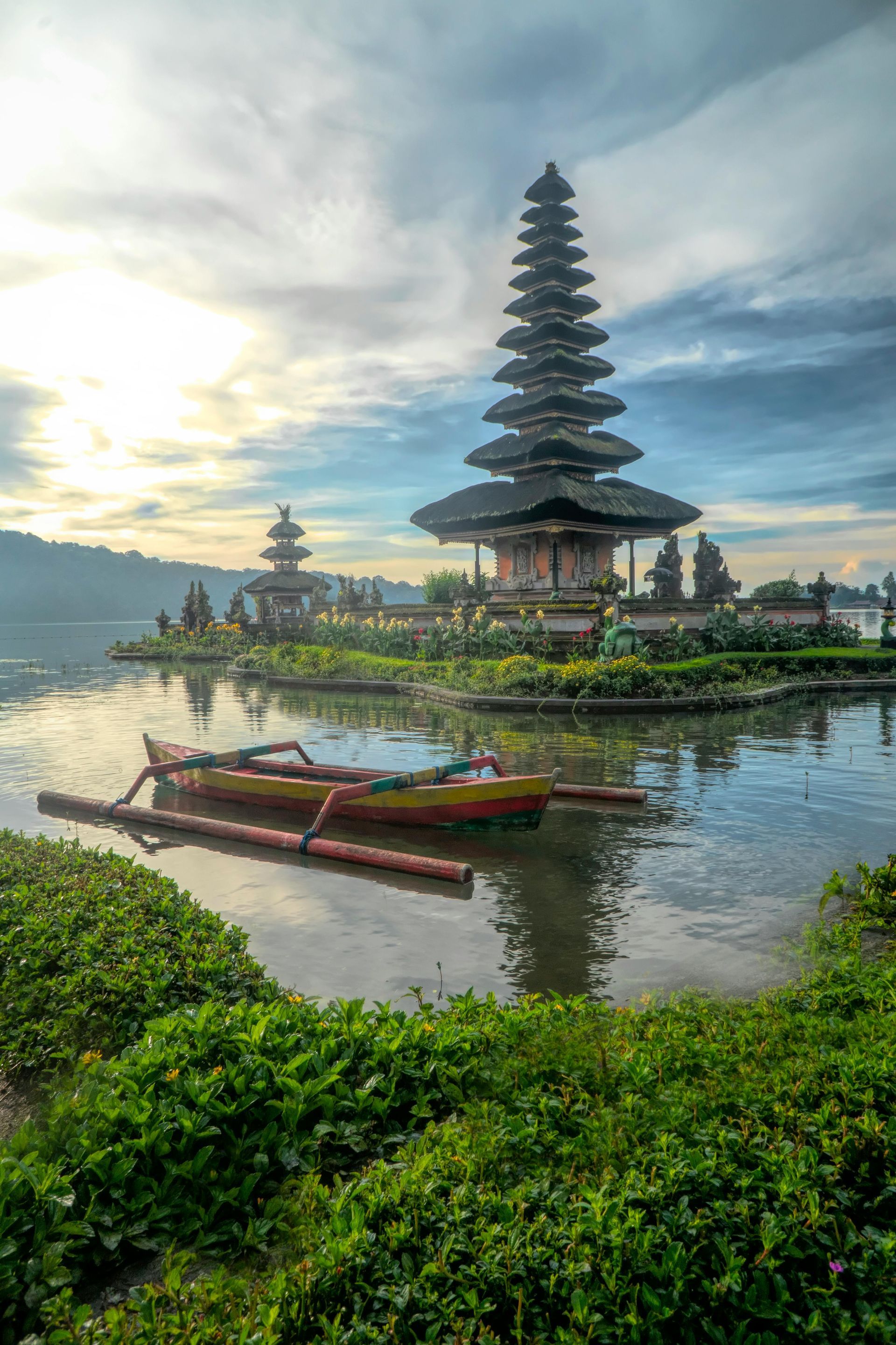 A boat is floating on a lake in front of the Ulun Danu Beratan Temple in Bali, Indonesia.