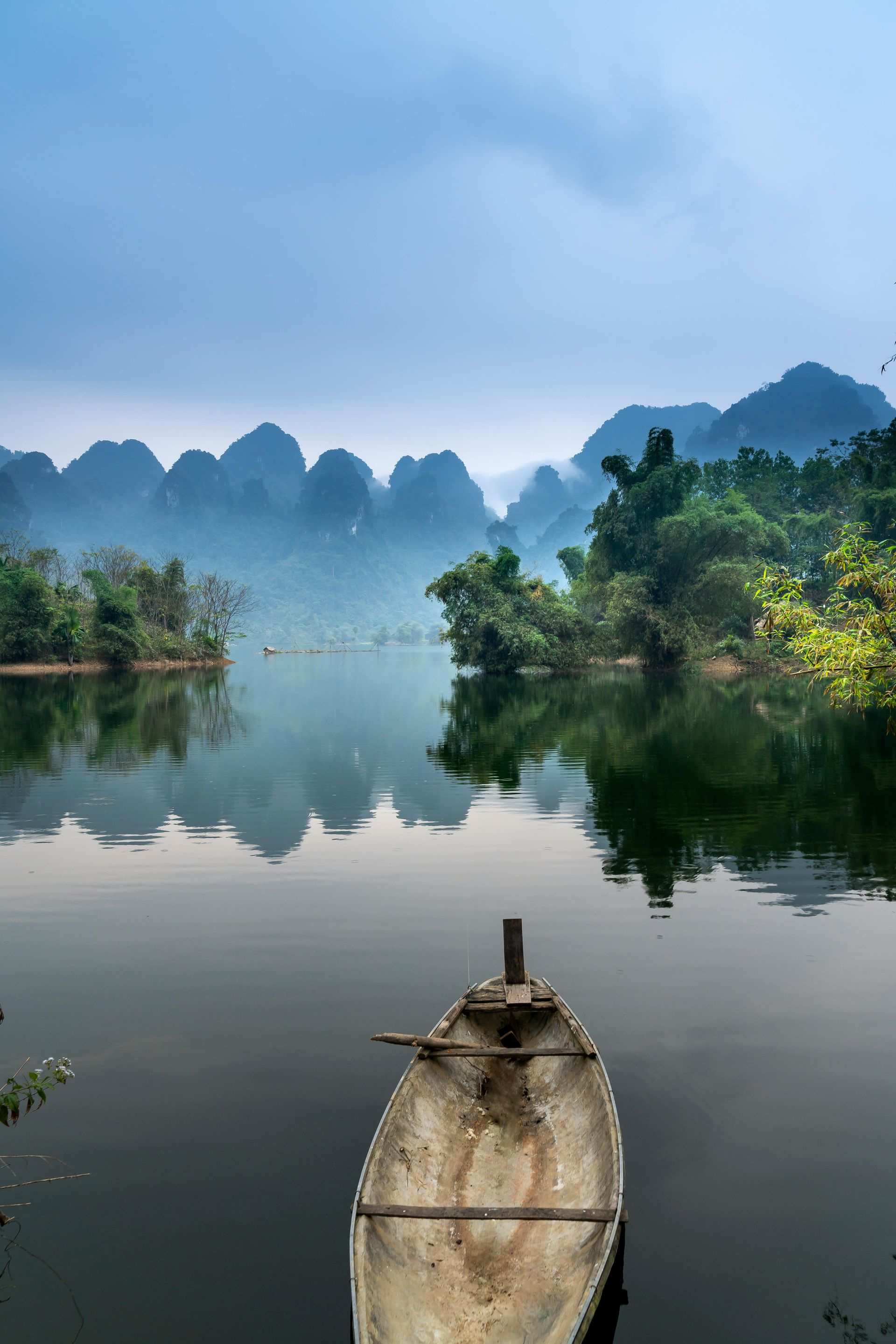 A boat is floating on a lake with mountains in the background in Asia.