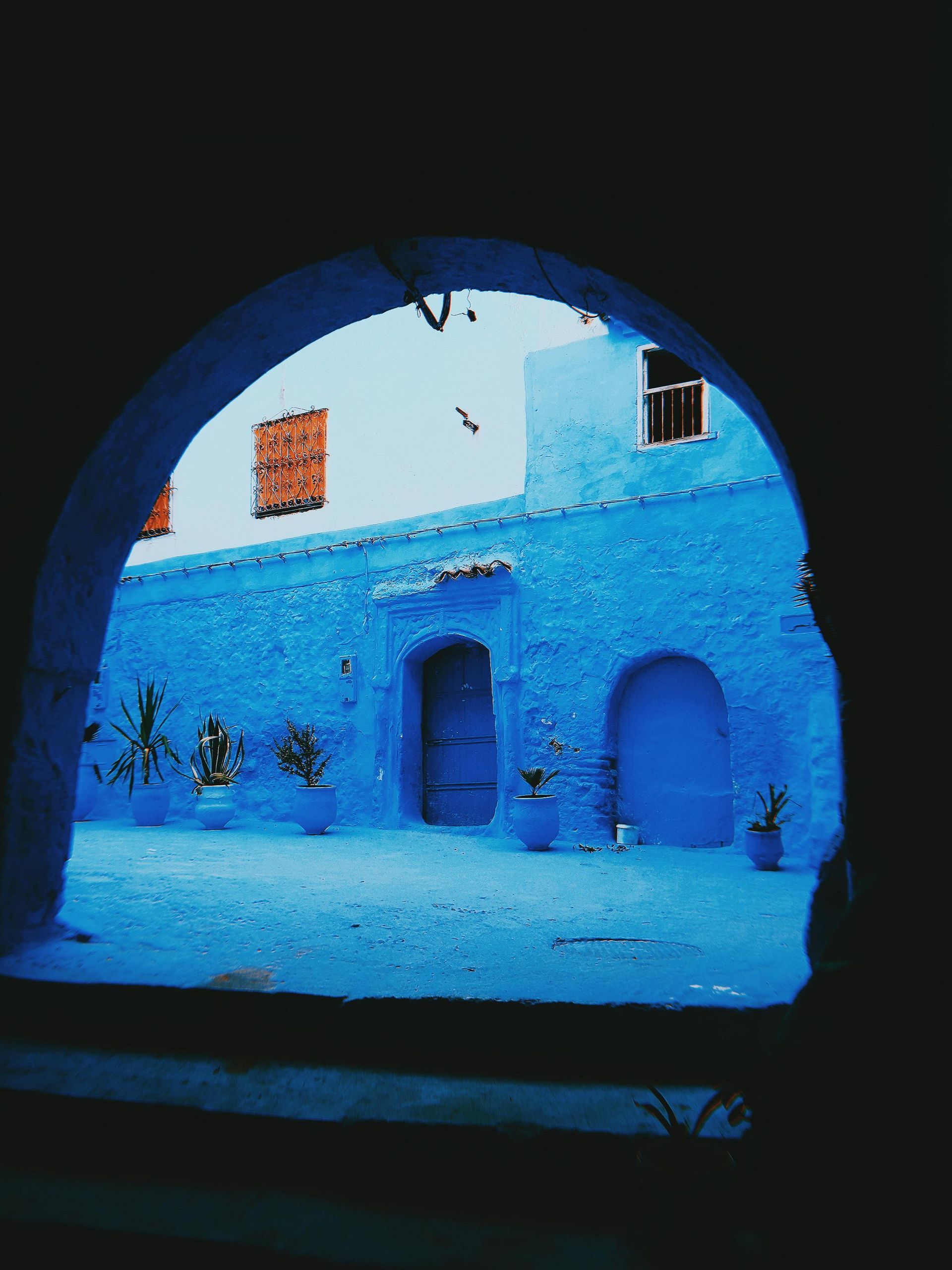 A view of a blue building through an archway in Morocco.