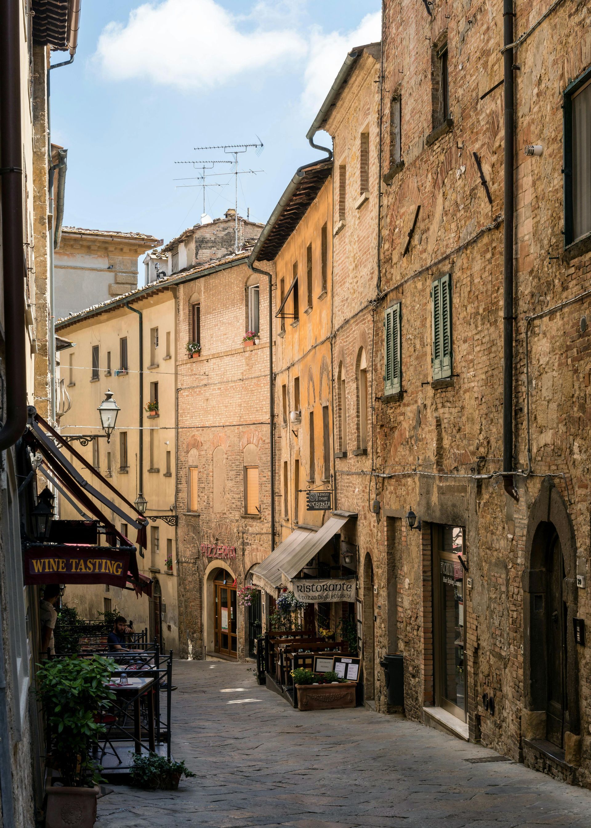 A narrow street with a sign that says ristorante on it in Tuscany, Italy.