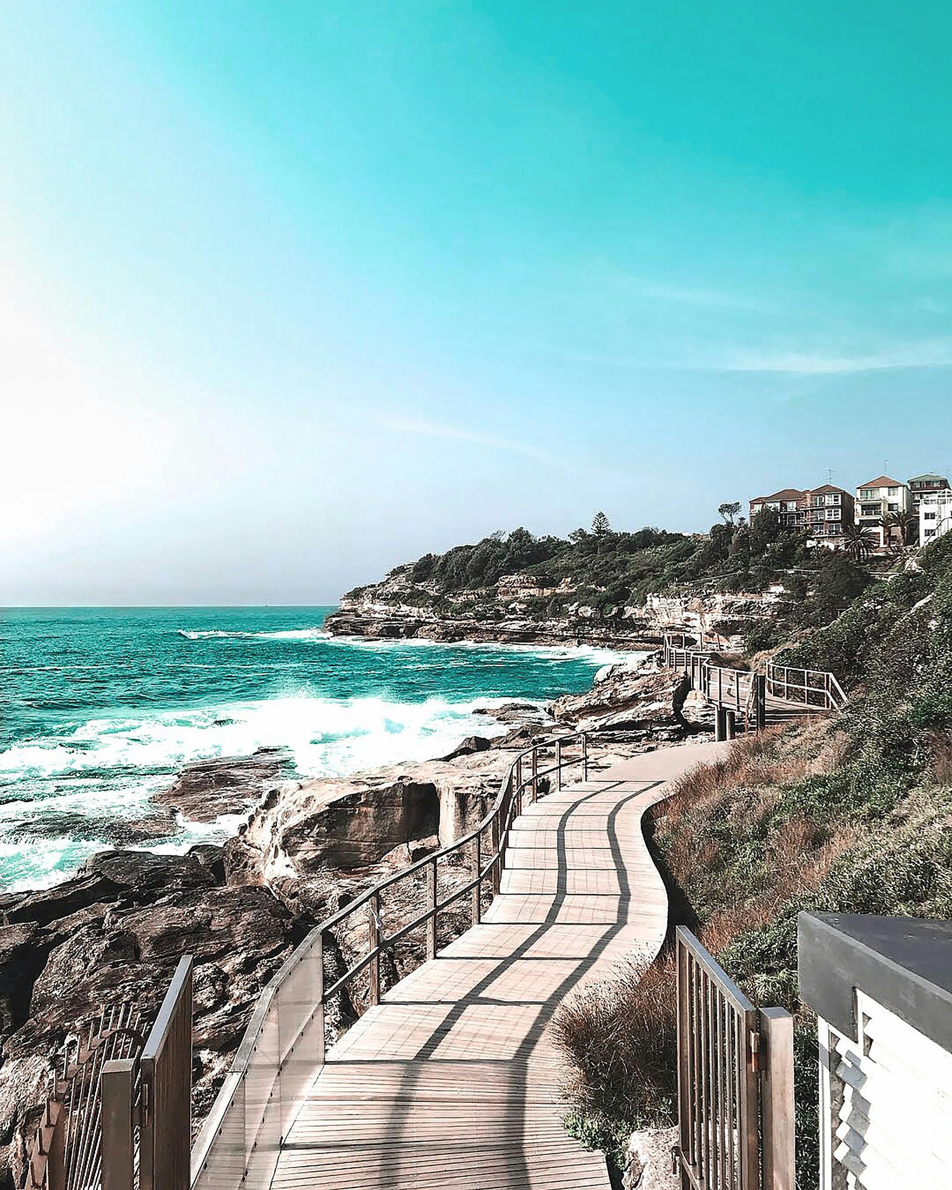 A wooden walkway leading to the ocean on a sunny day in Australia.