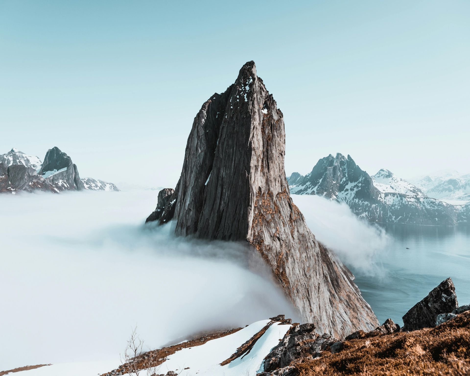 A mountain covered in snow and clouds with a blue sky in the background in Norway.