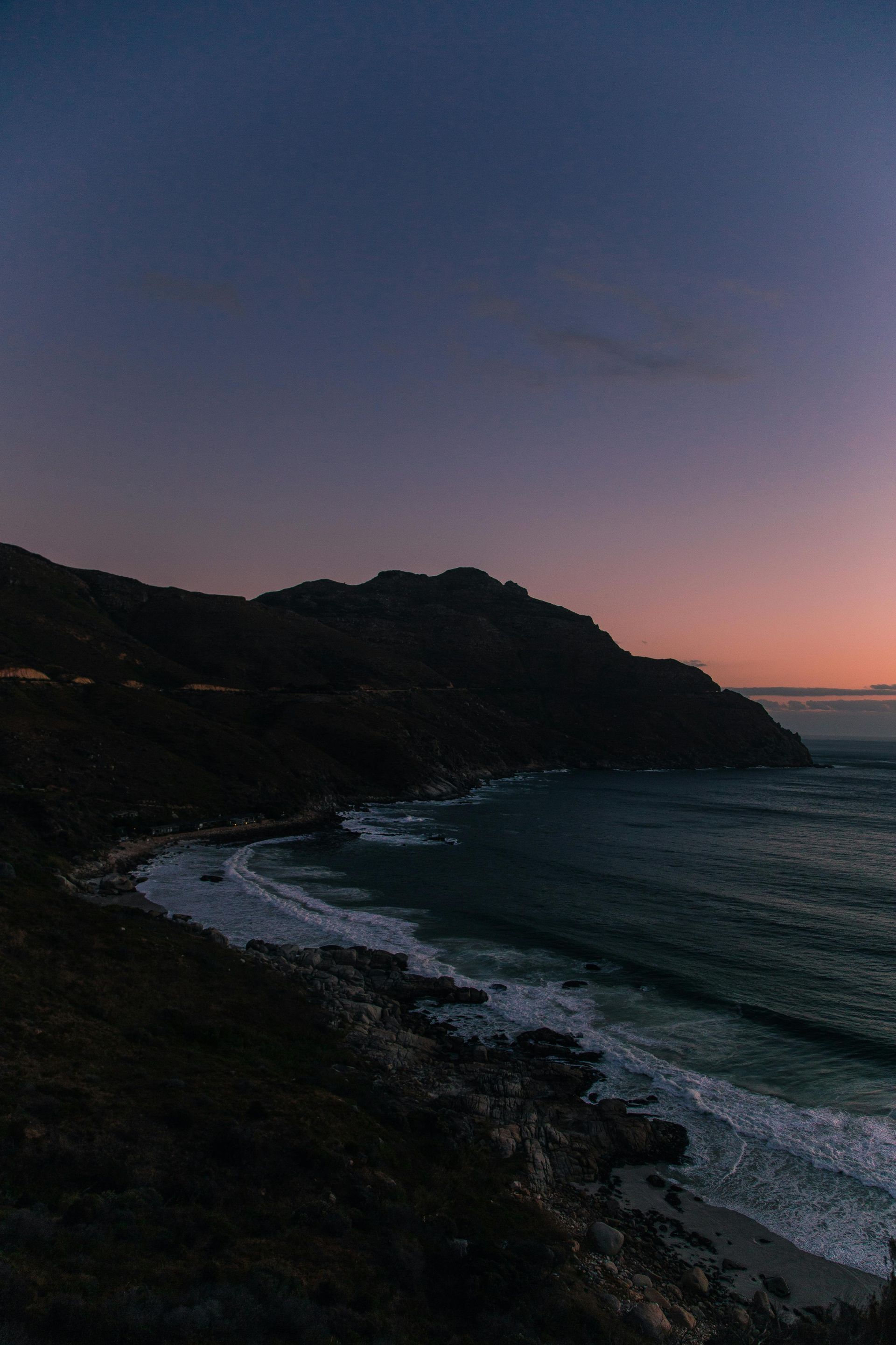 An aerial view of a beach at sunset with mountains in the background in South Africa.