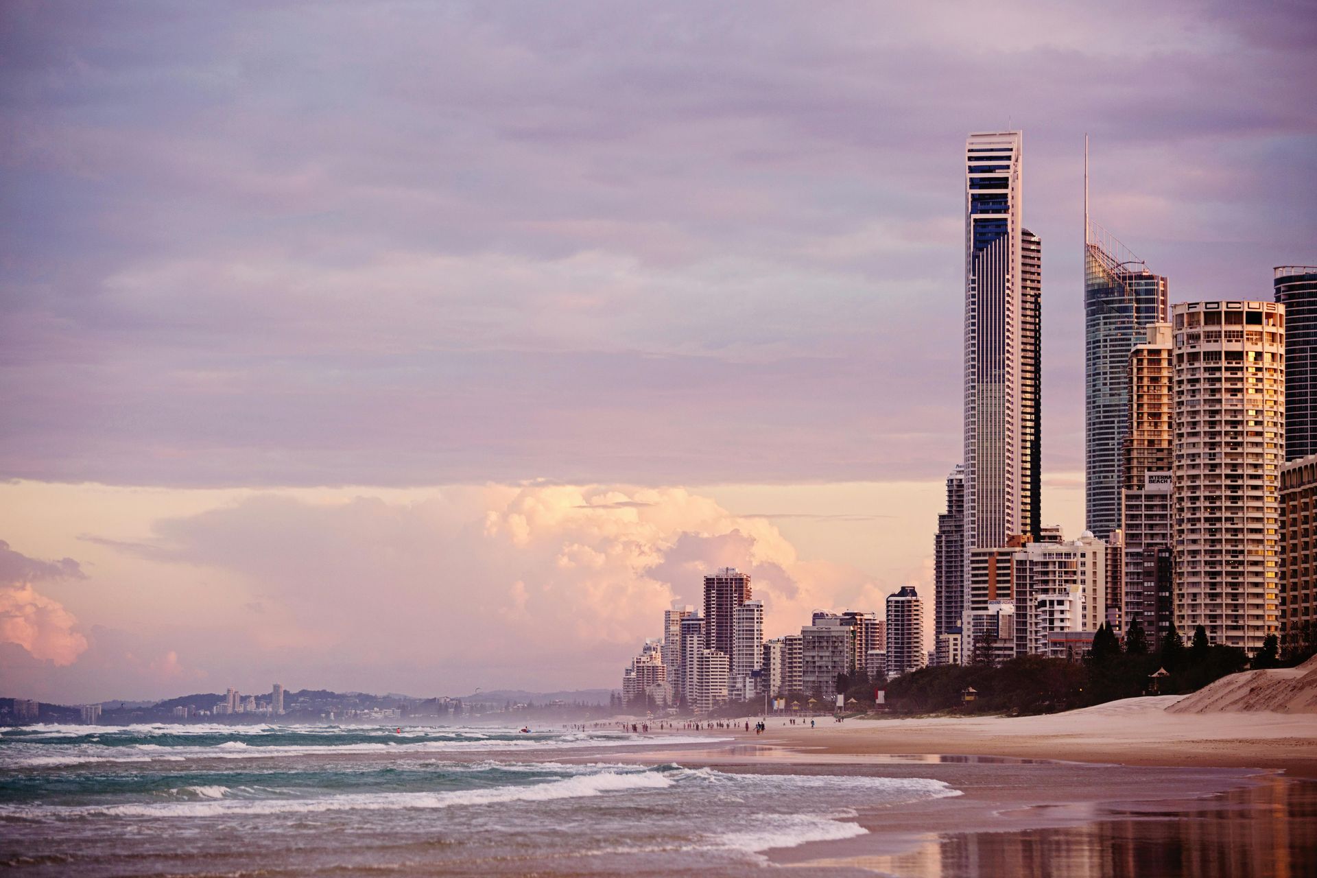 A beach with a city skyline in the background at sunset in Australia.