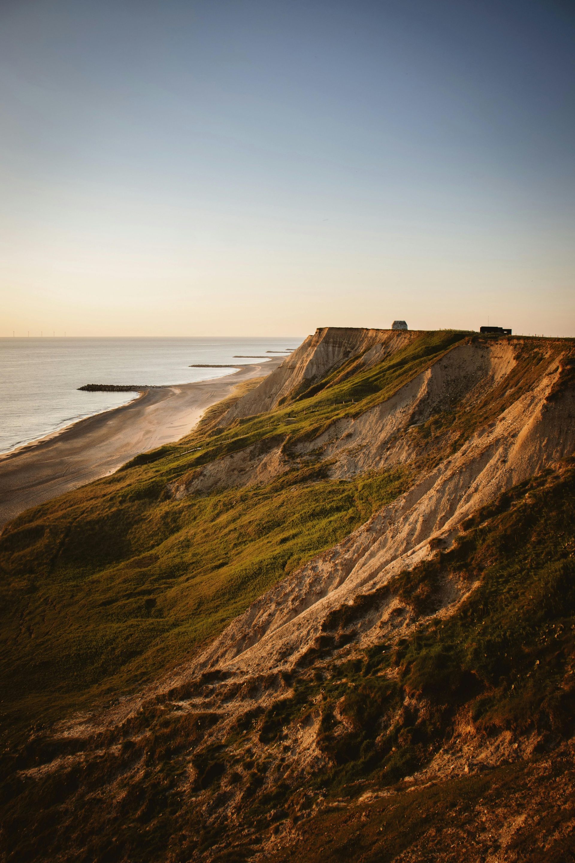 A view of a cliff overlooking the ocean at sunset in Denmark.