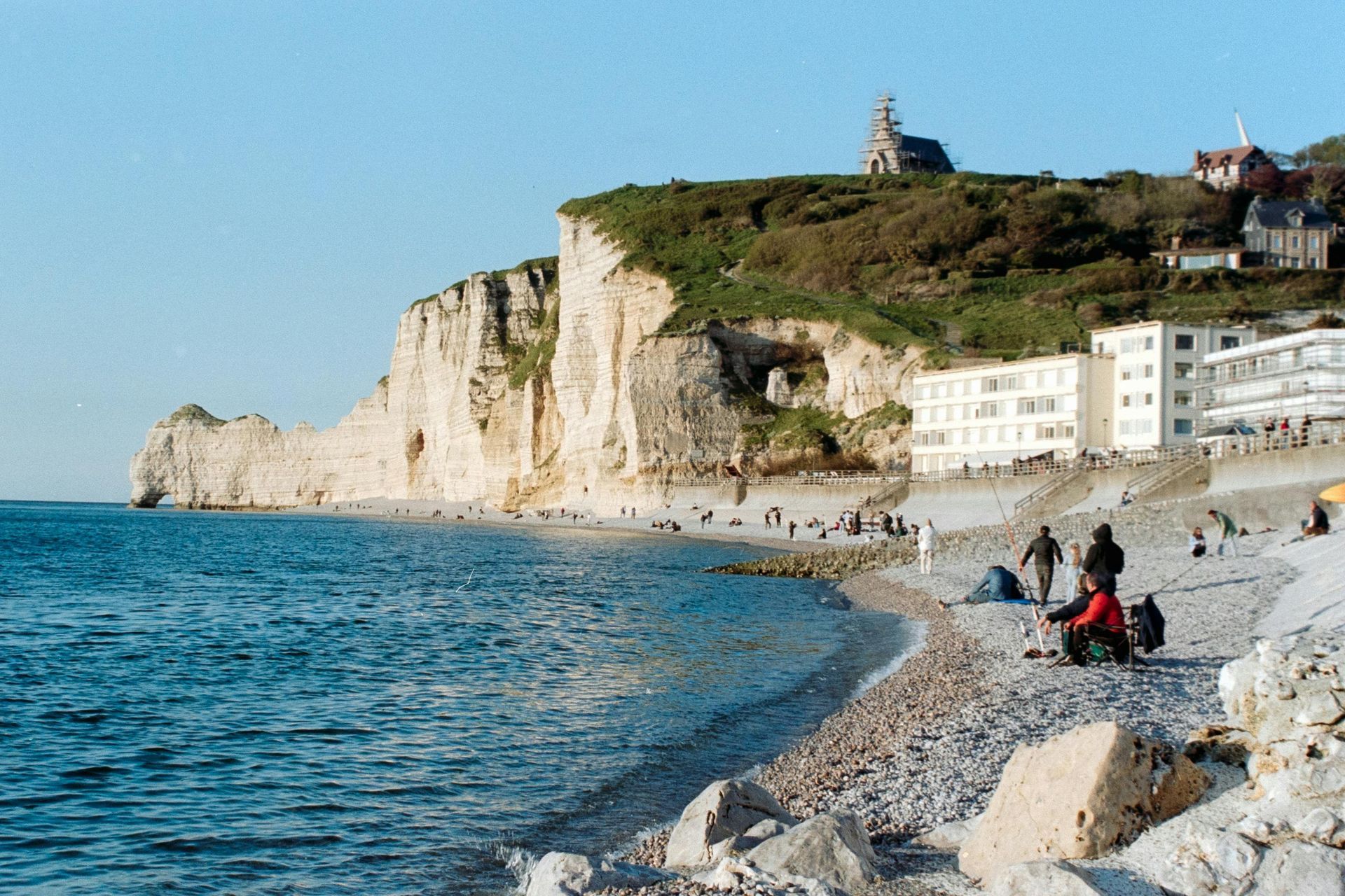 A beach with a cliff in the background and people on it in Normandy, France.