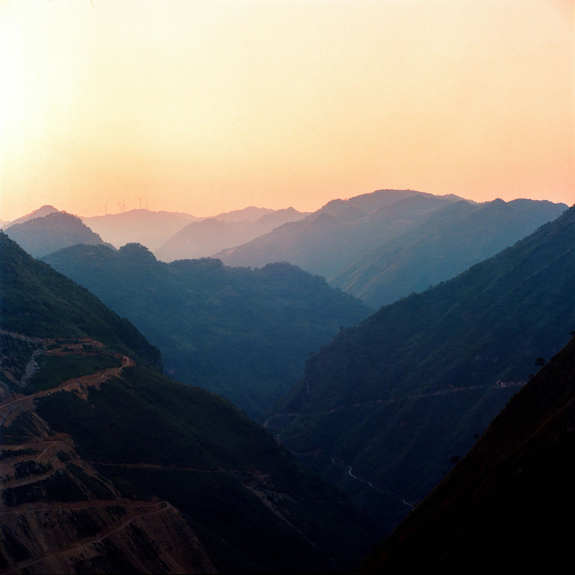 A sunset over a valley with mountains in the background