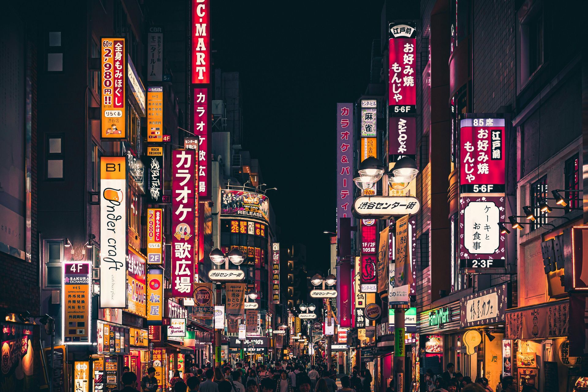 A crowd of people are walking down a busy street at night in Japan.