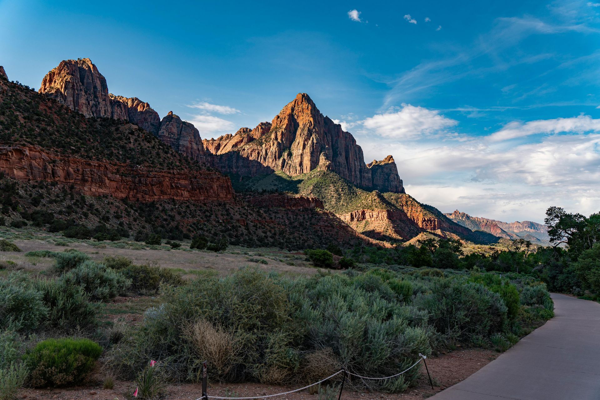 A road going through a desert with mountains in the background at Pa'rus Trail Zion National Park in Utah.