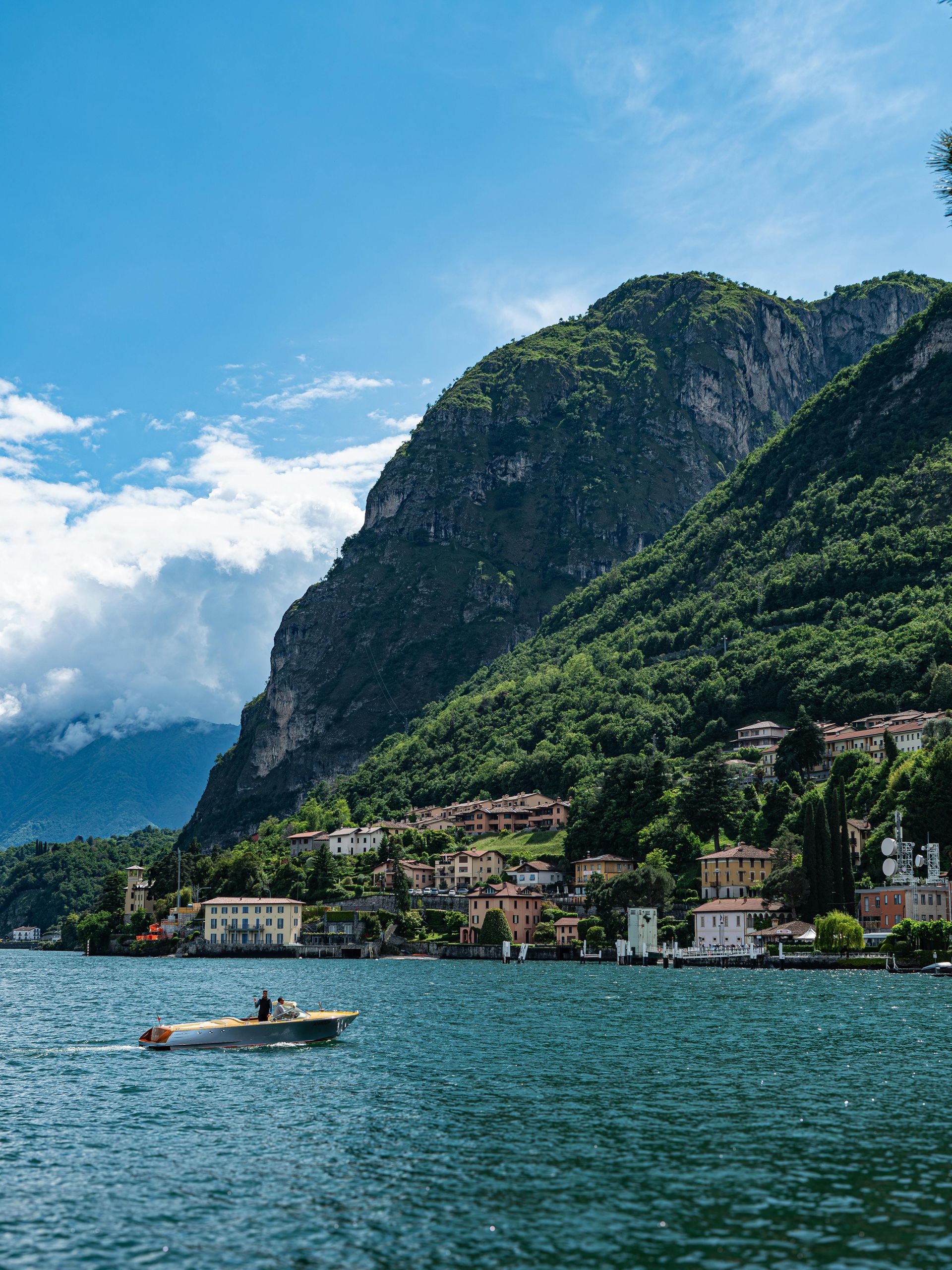 A boat is floating on Lake Como with mountains in the background in Italy.