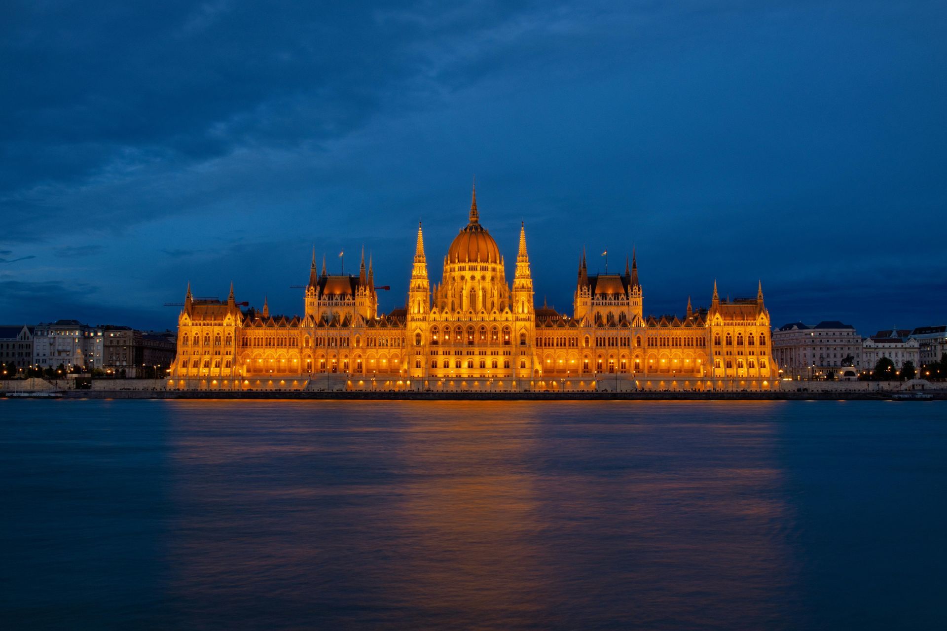 The Budapest parliament is lit up at night and is reflected in The Danube River.