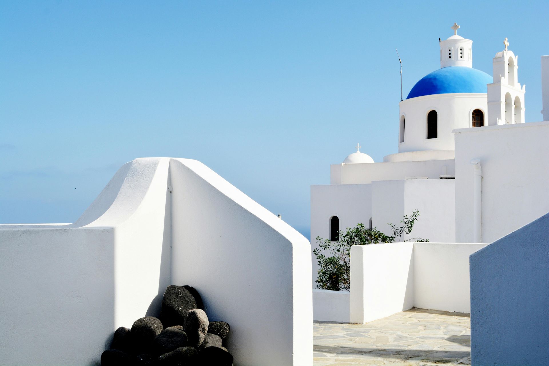 A white building with a blue dome on top of it in Santorini, Greece.