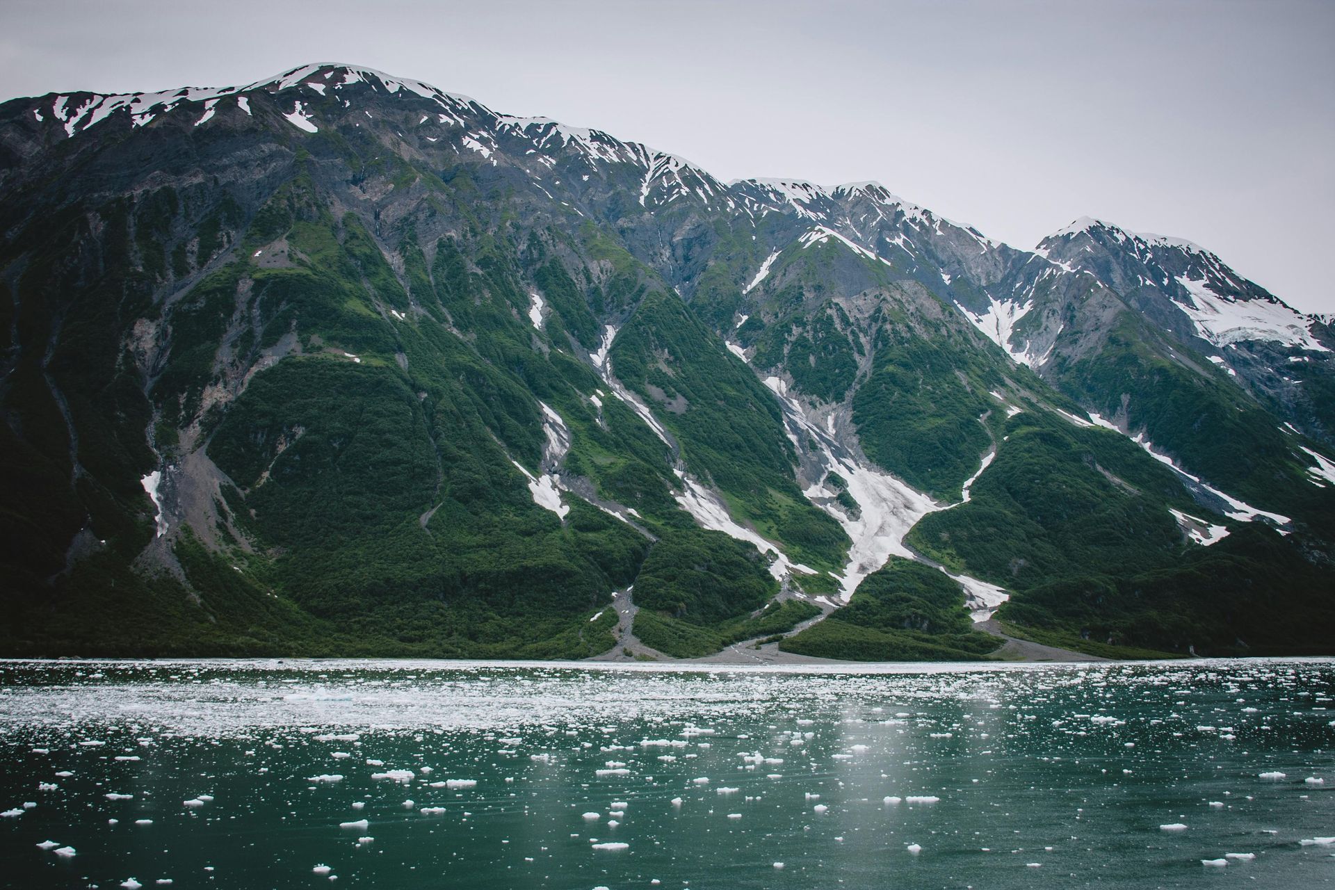 A lake with mountains in the background and trees on the shore in Alaska. 