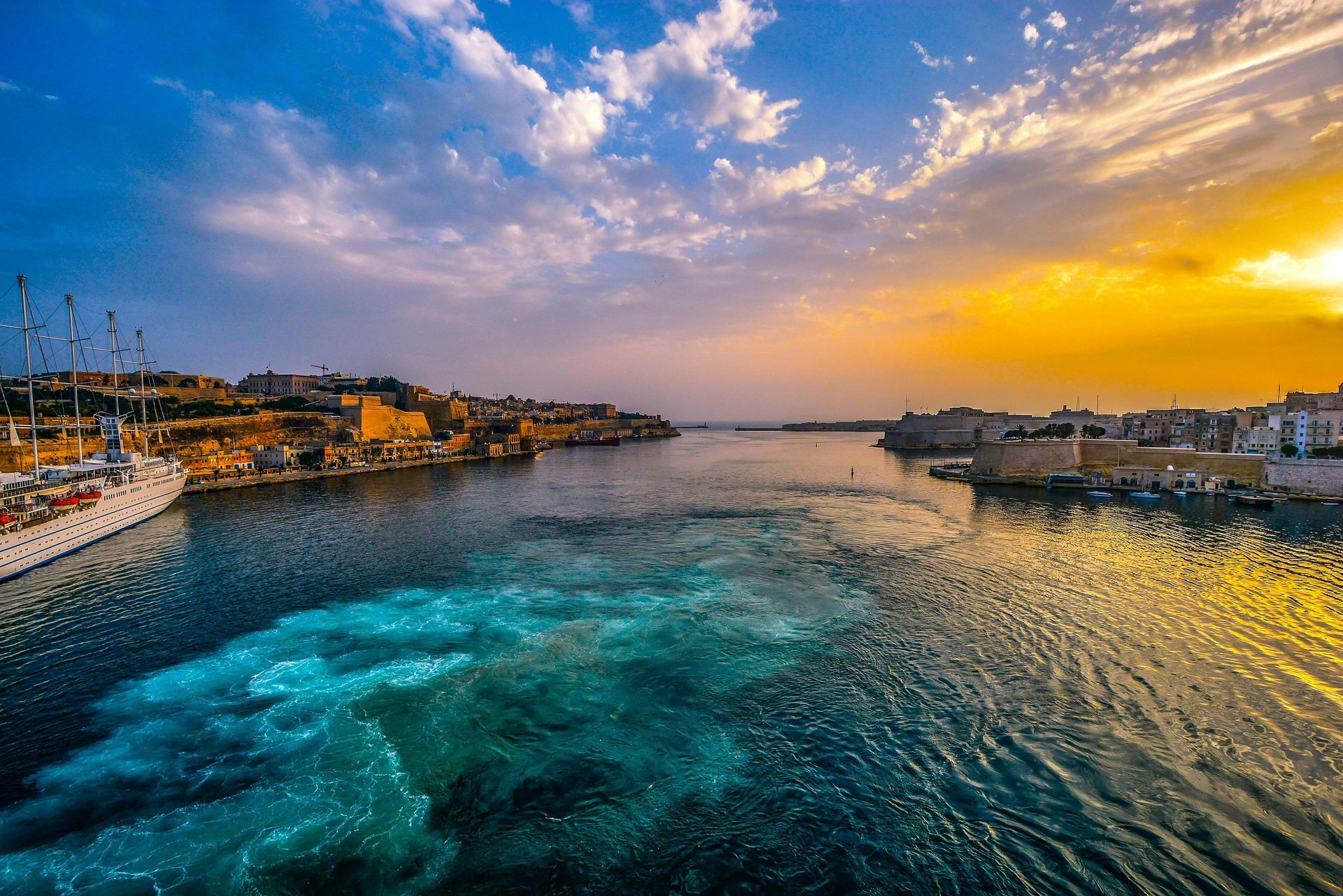 An aerial view of the mediterranean ocean with a city in the background at sunset.