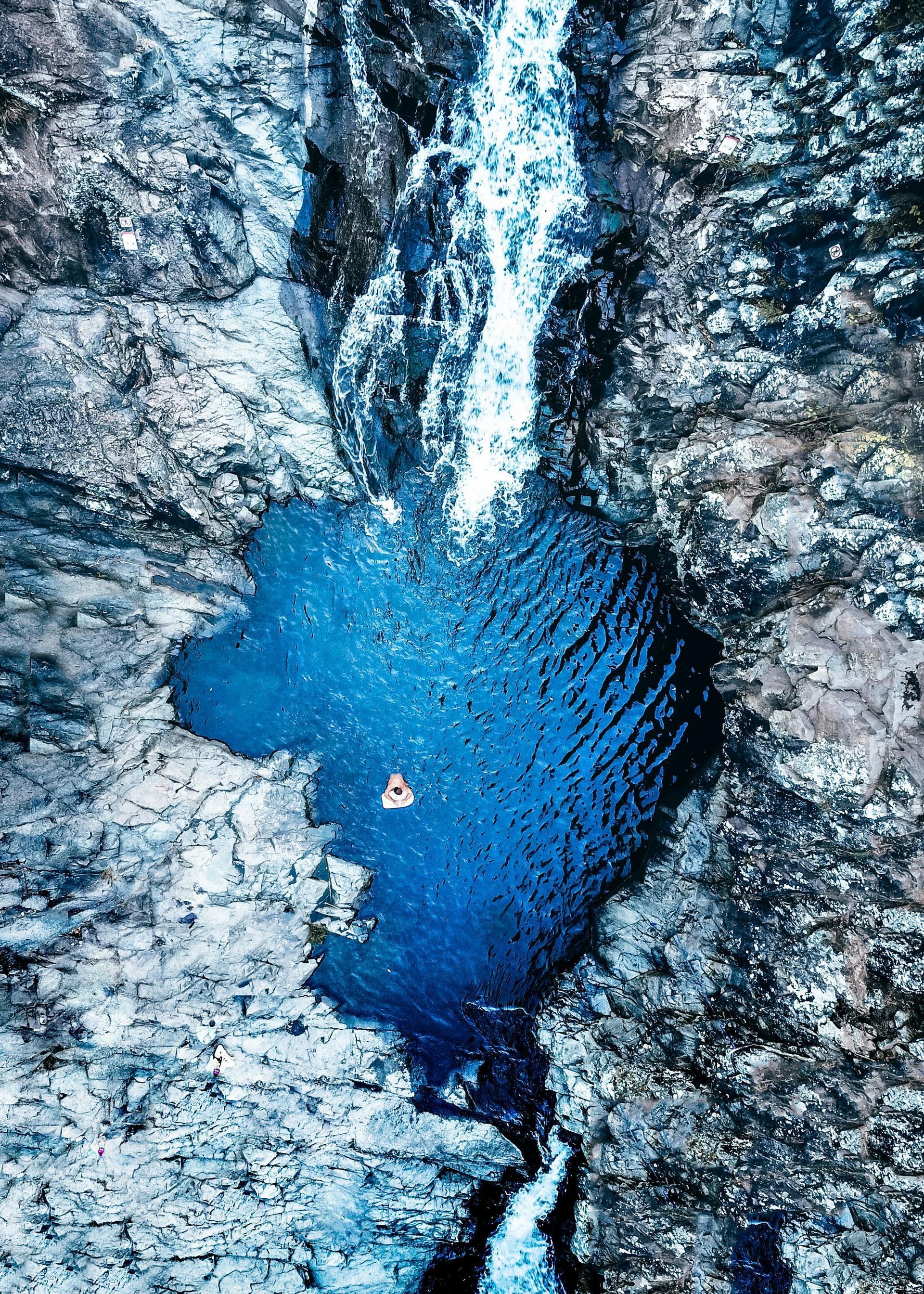 A waterfall is coming down a cliff into a pool of blue water in Australia.