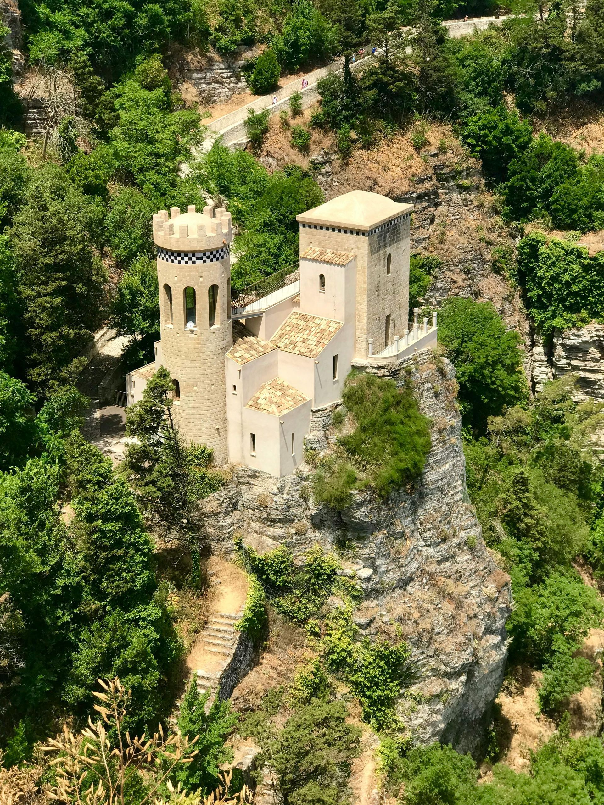 An aerial view of a castle on top of a hill surrounded by trees in Sicily, Italy.