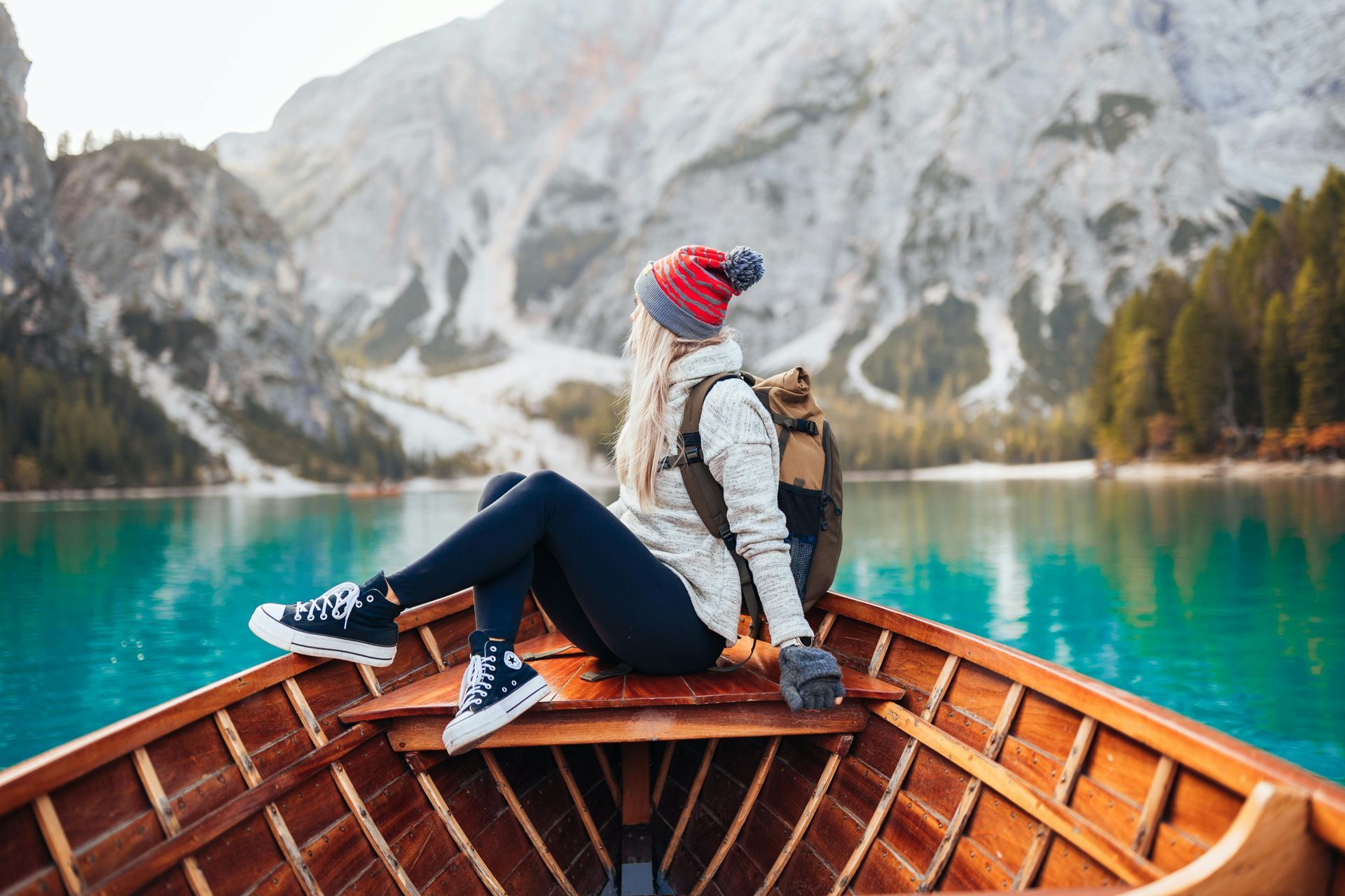 A woman is sitting in a wooden boat on a lake in The Dolomites in Italy.