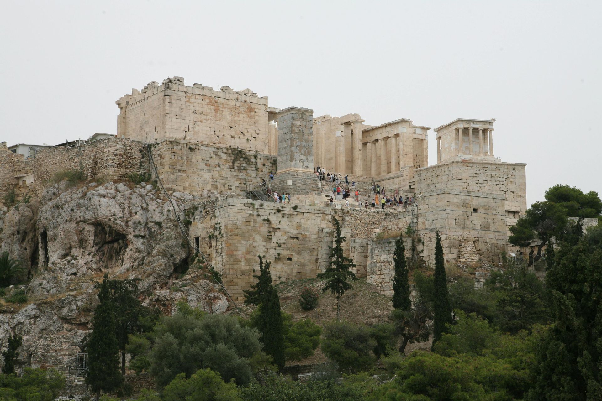 A castle on top of a hill with trees in the foreground in Athens, Greece.