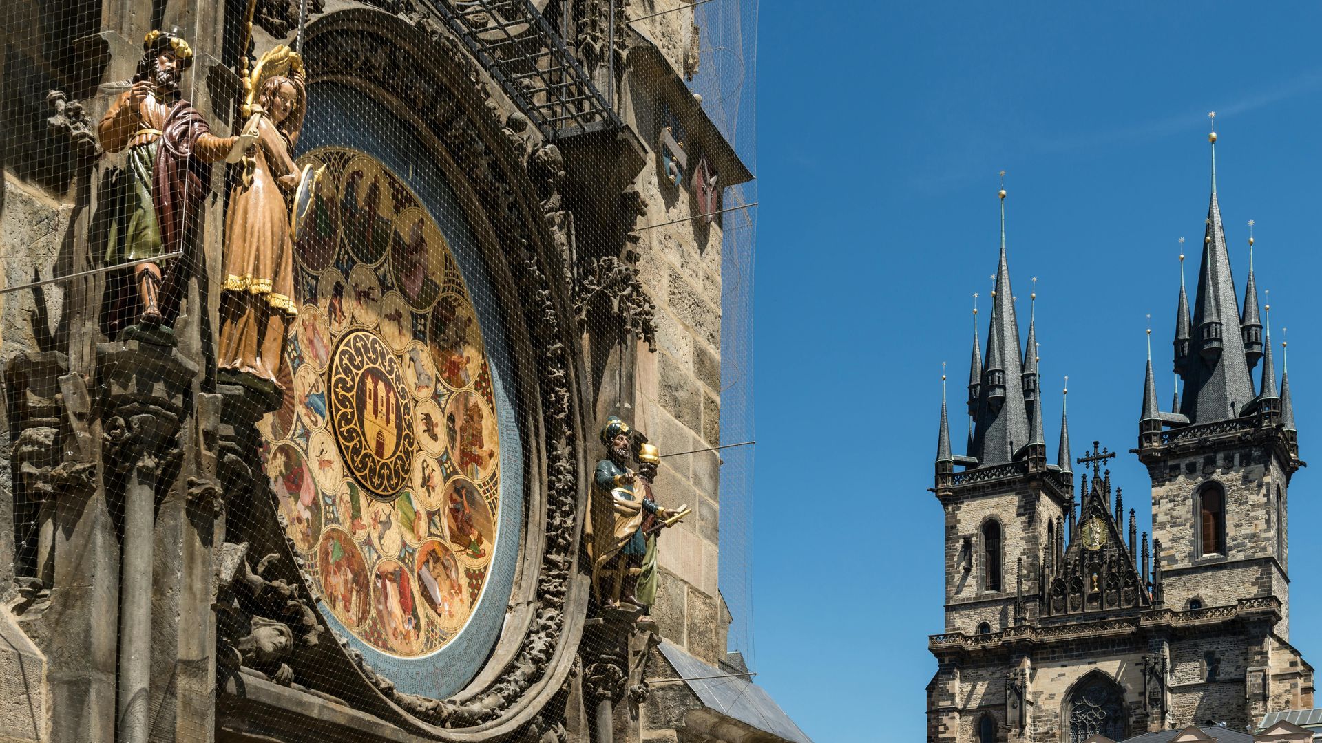 The Prague Astronomical Clock is on the side of a building with a blue sky in the background in Prague. 