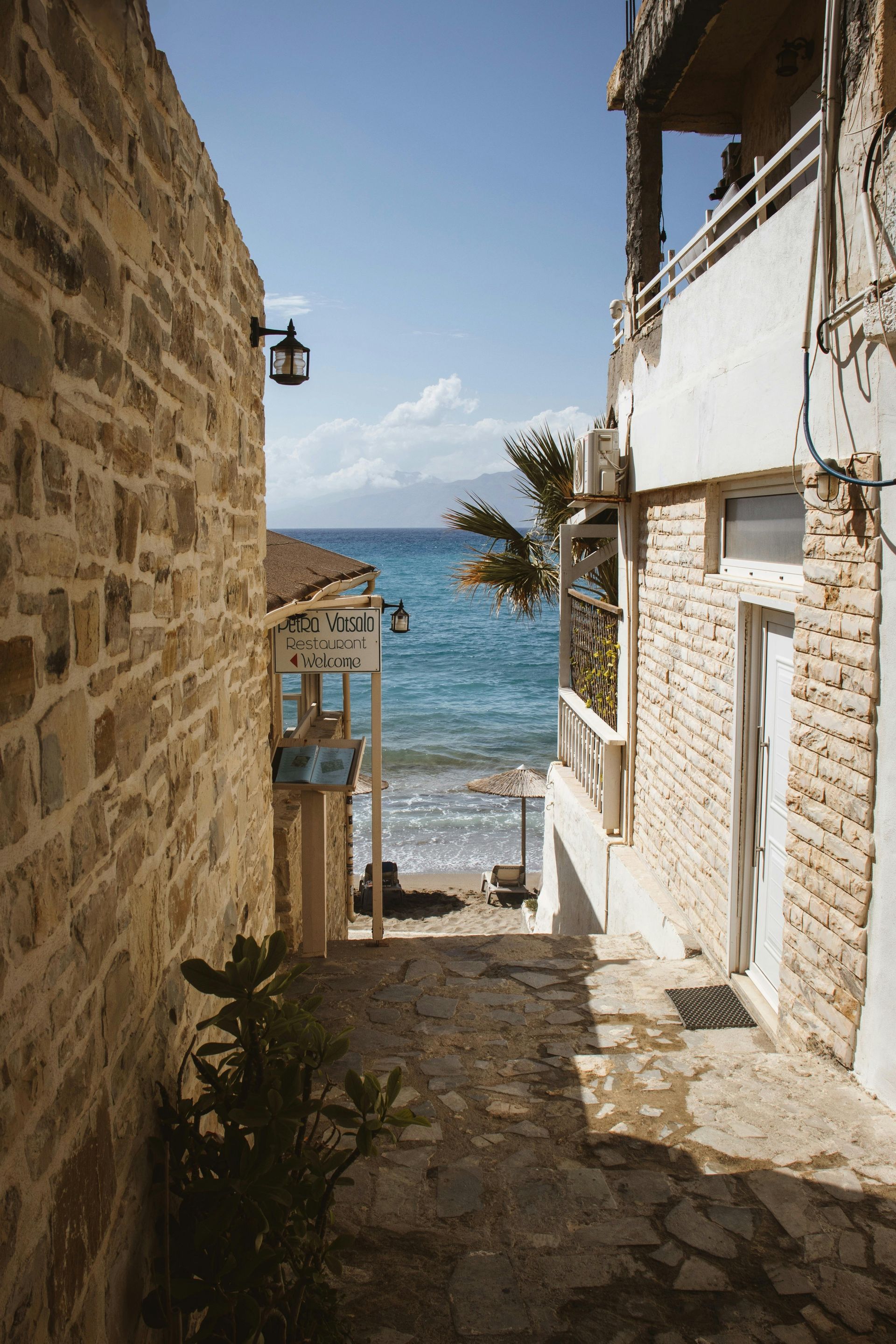 There is a narrow alleyway leading to the ocean in Crete, Greece.