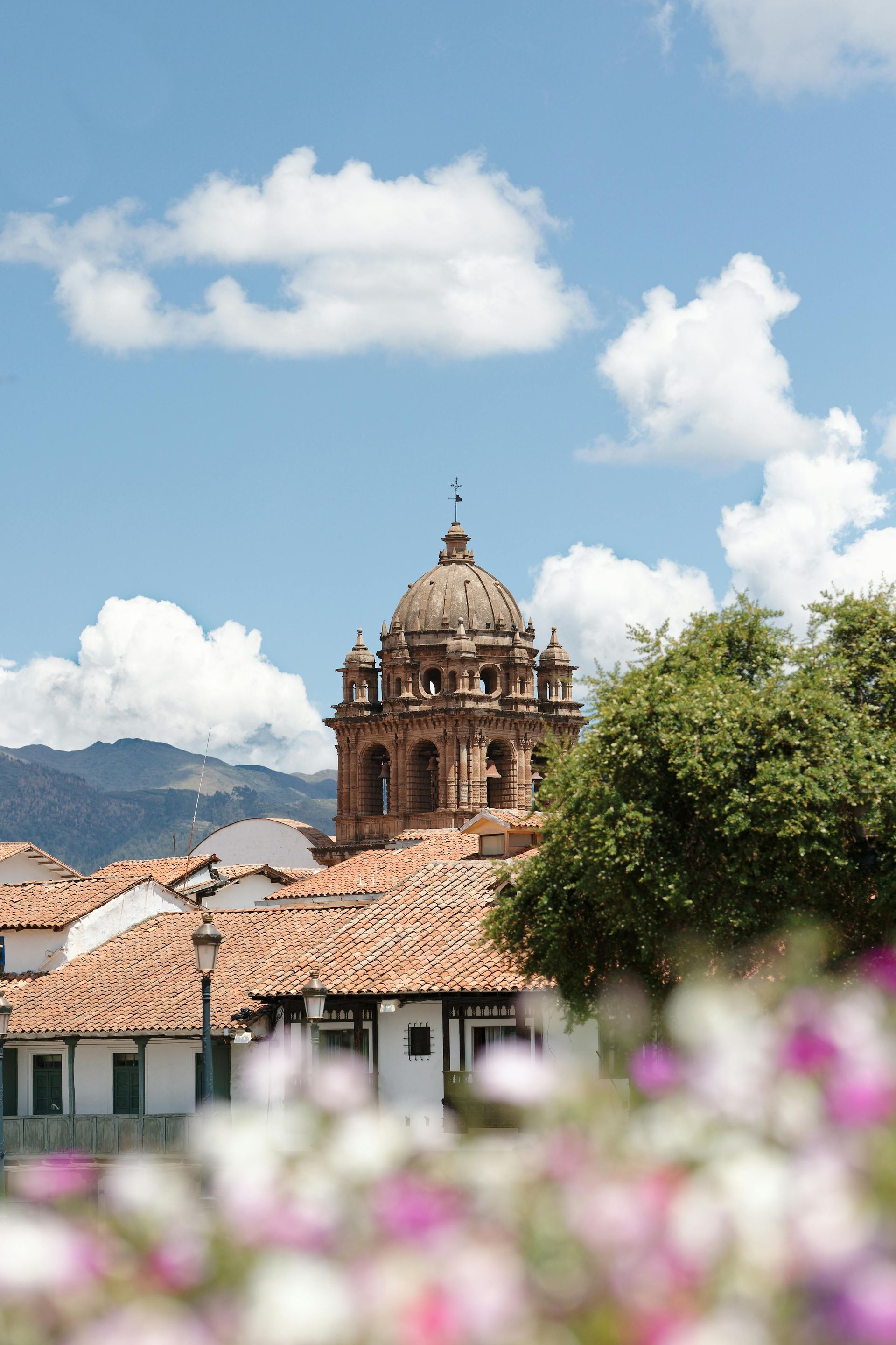 A church with a dome on top of it is surrounded by flowers and trees in Peru.