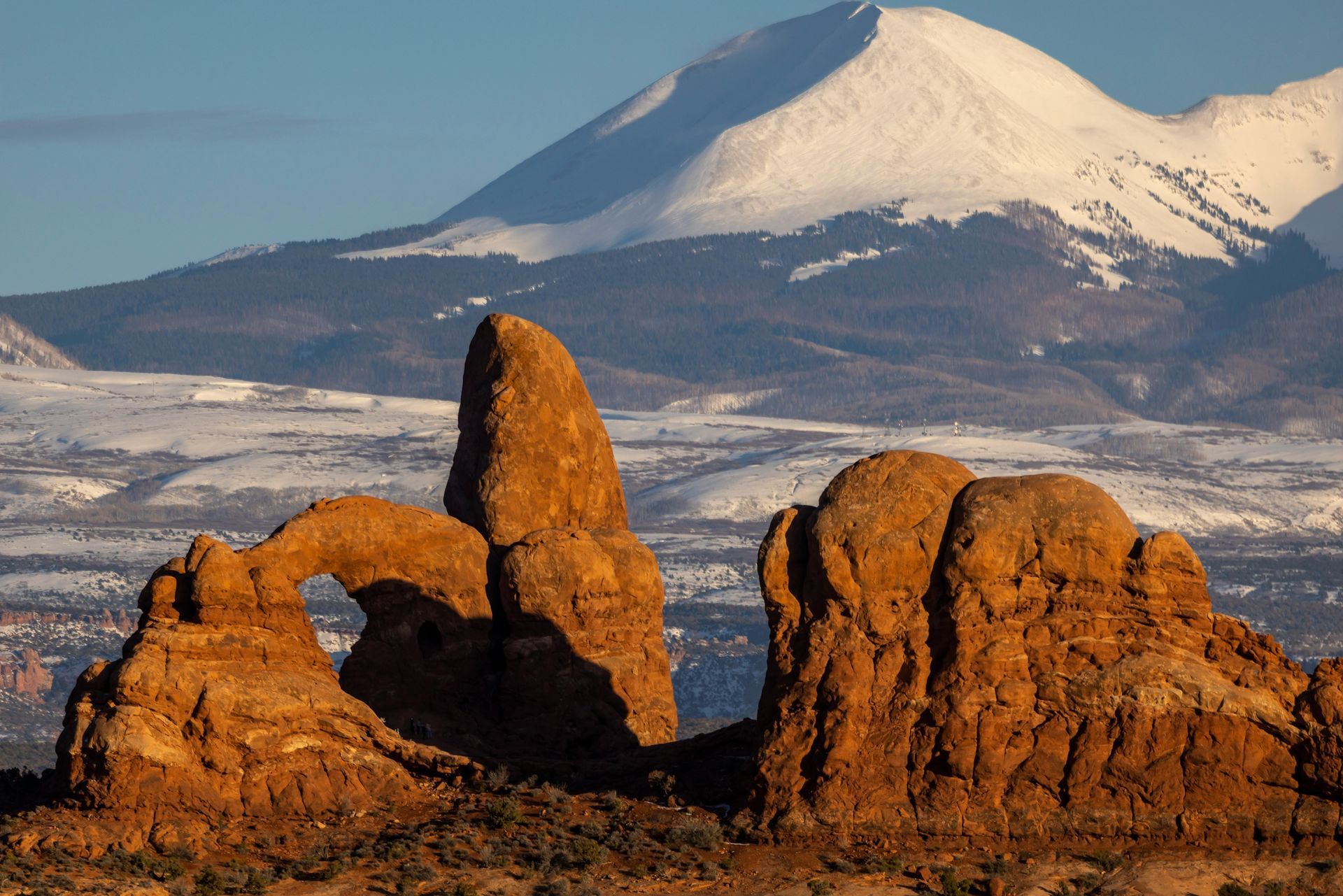 A rock formation in the desert with mountains in the background at Arches National Park in Utah.