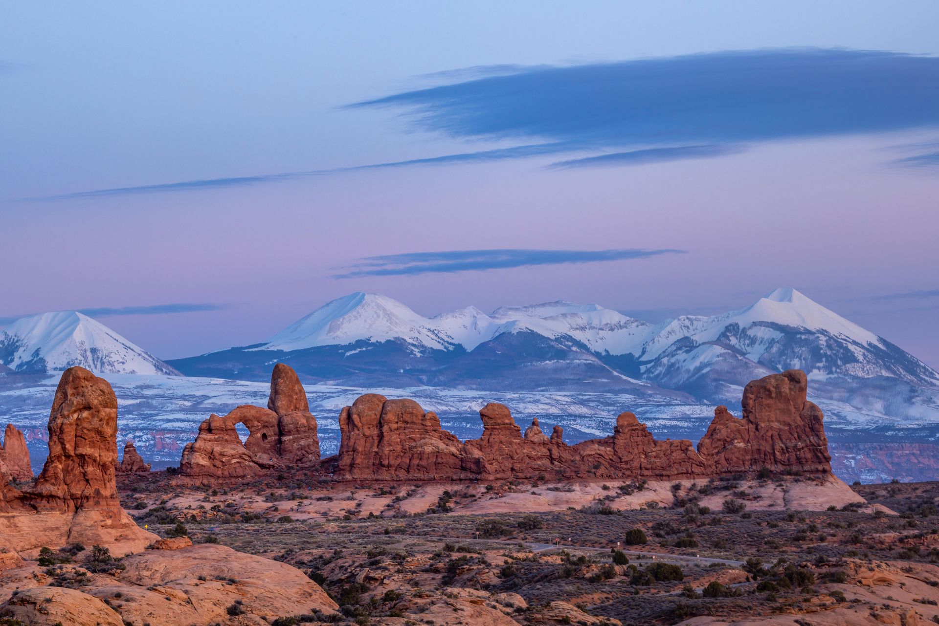 A desert landscape with rocks and mountains in the background at Arches National Park in Utah.