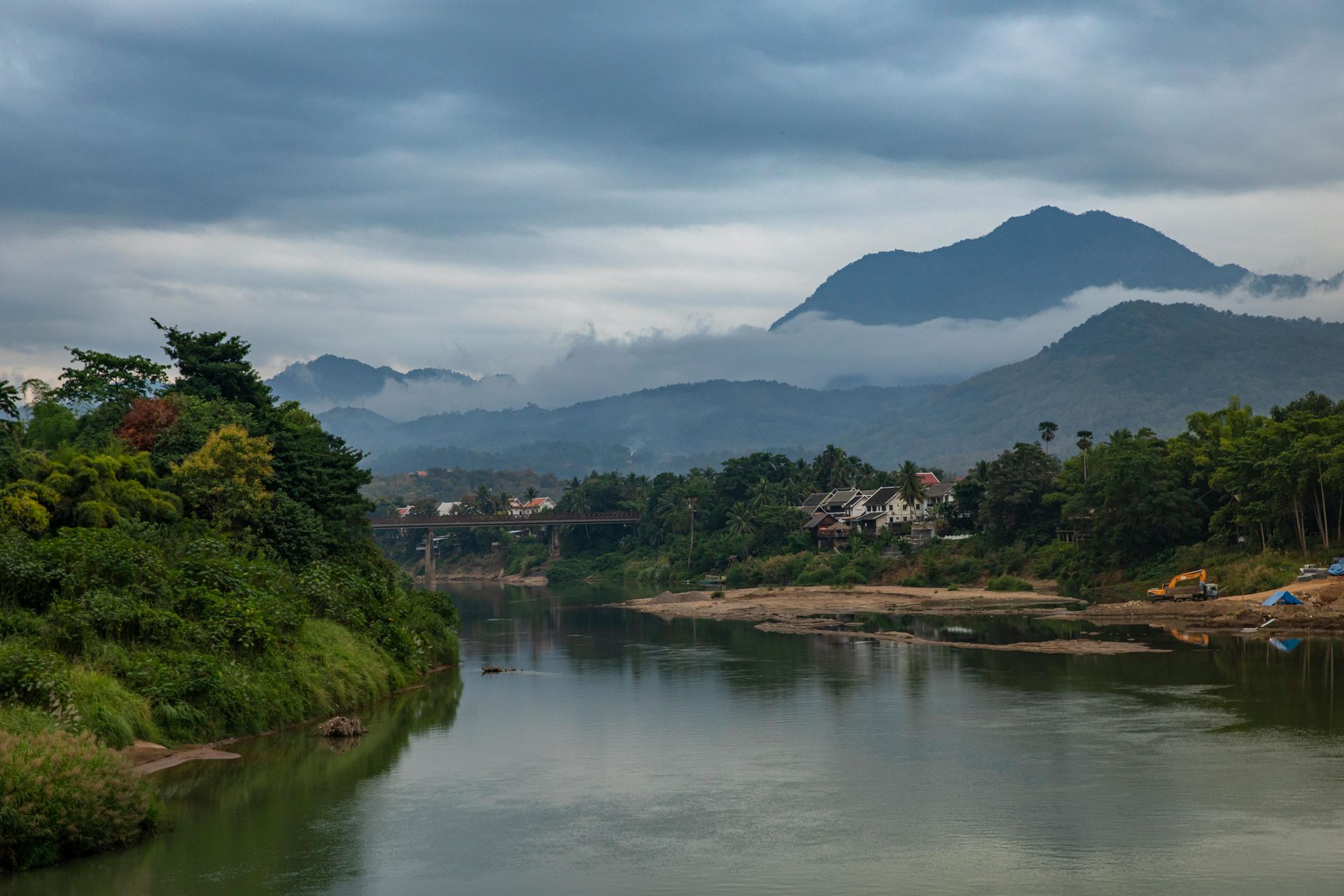 A river with mountains in the background and a bridge in the foreground in Laos.