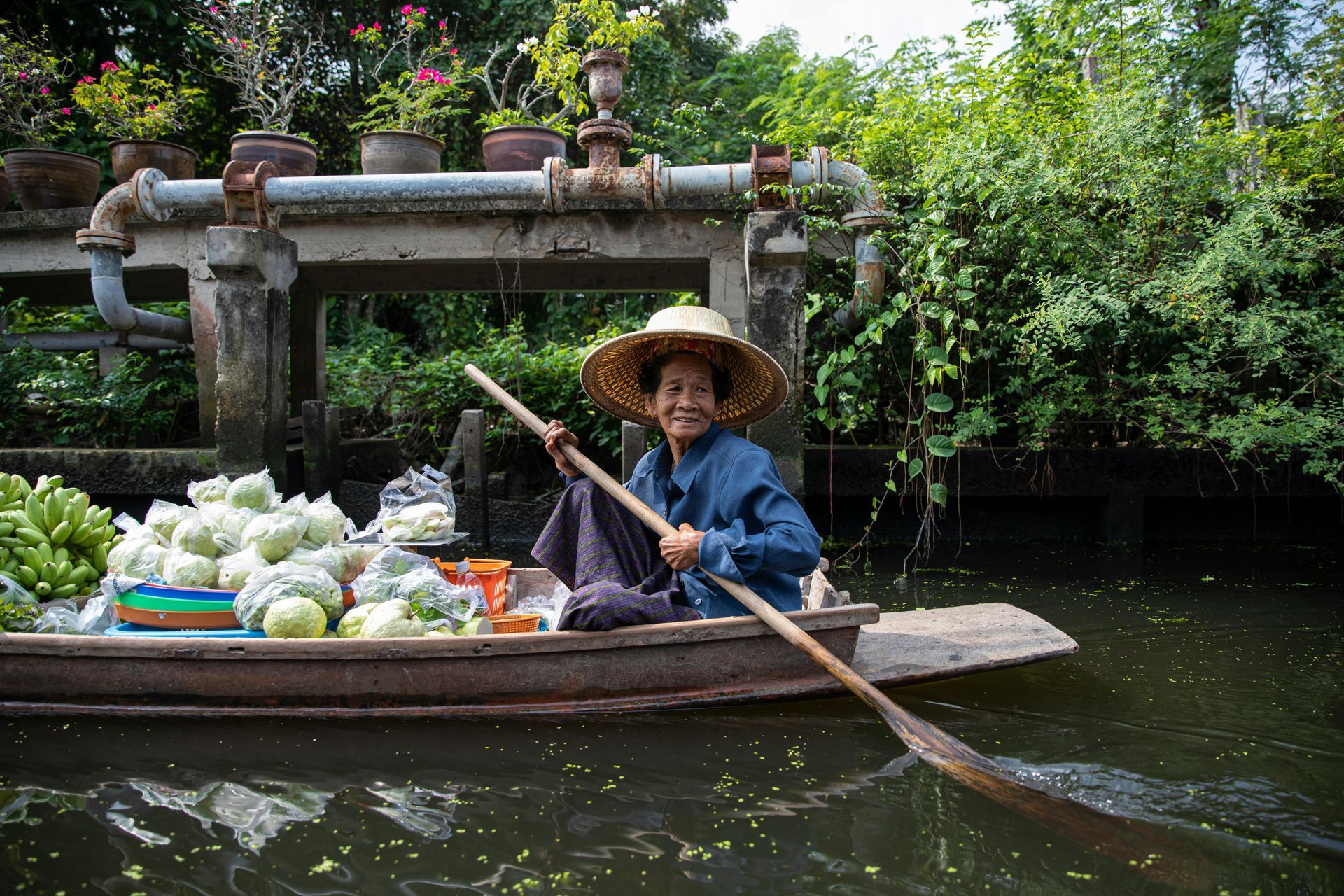 A man is rowing a boat with vegetables on it in Laos.