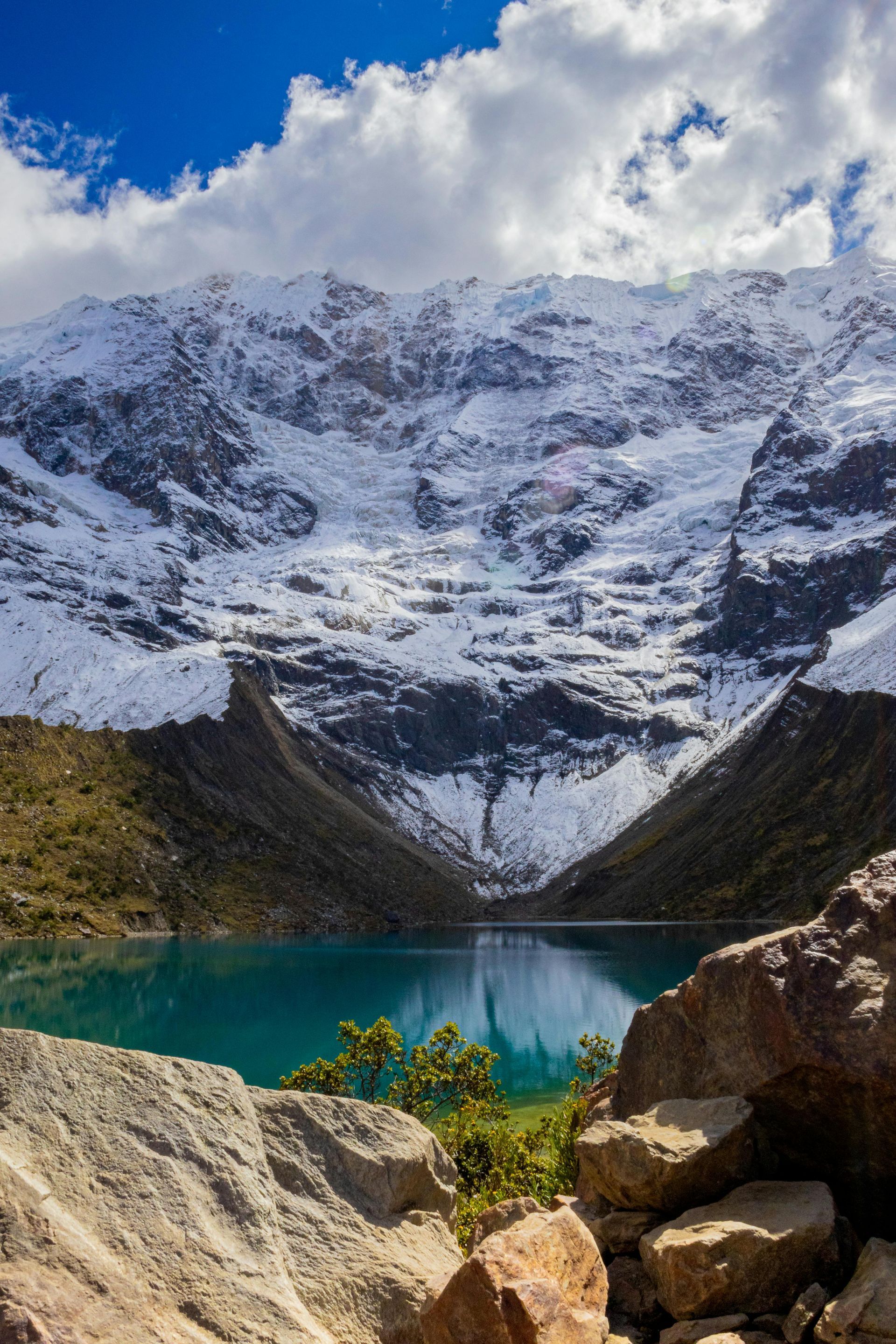 A mountain covered in snow with a lake in the foreground in Peru.