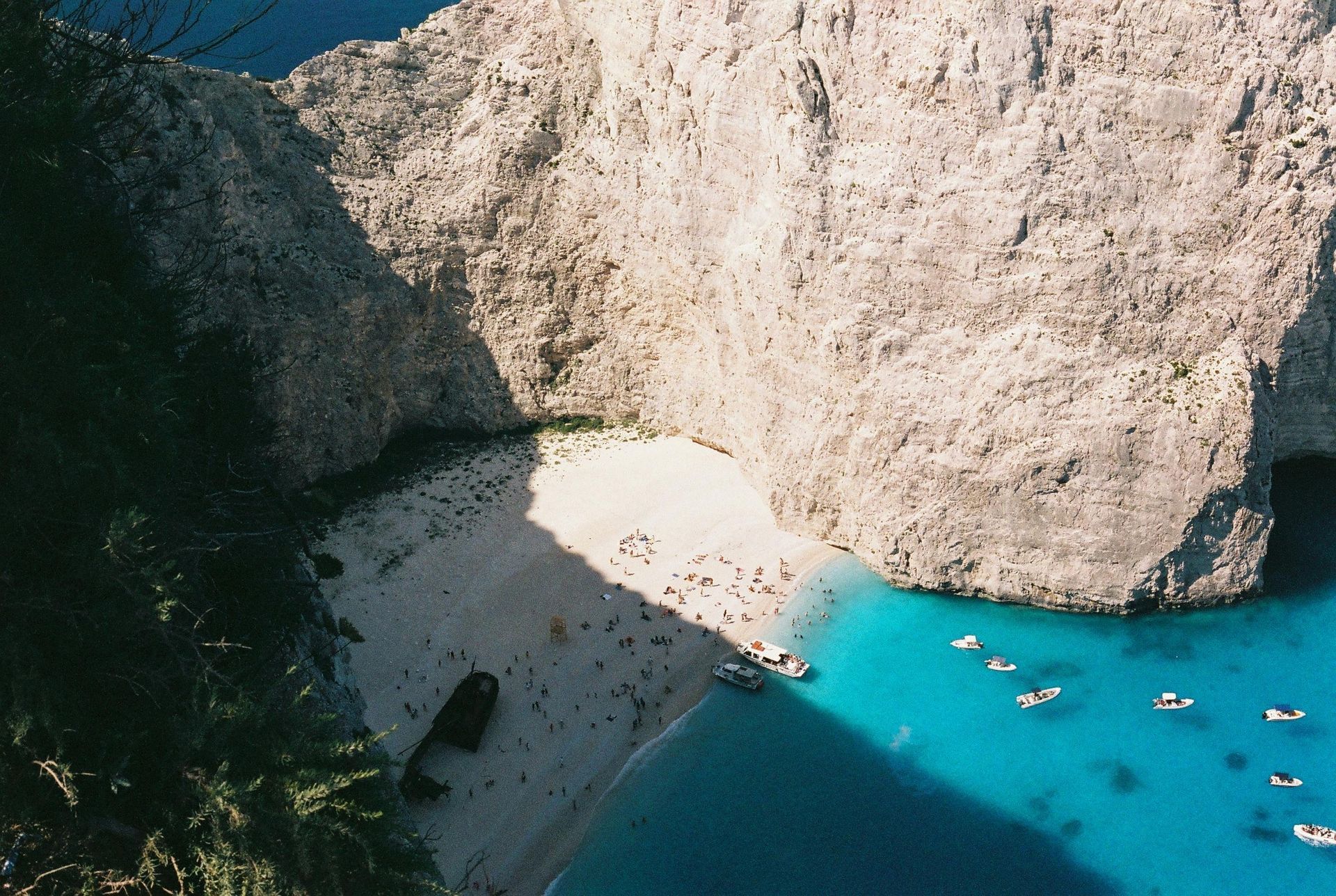 An aerial view of Navagio beach with boats in the water in Zakynthos, Greece.