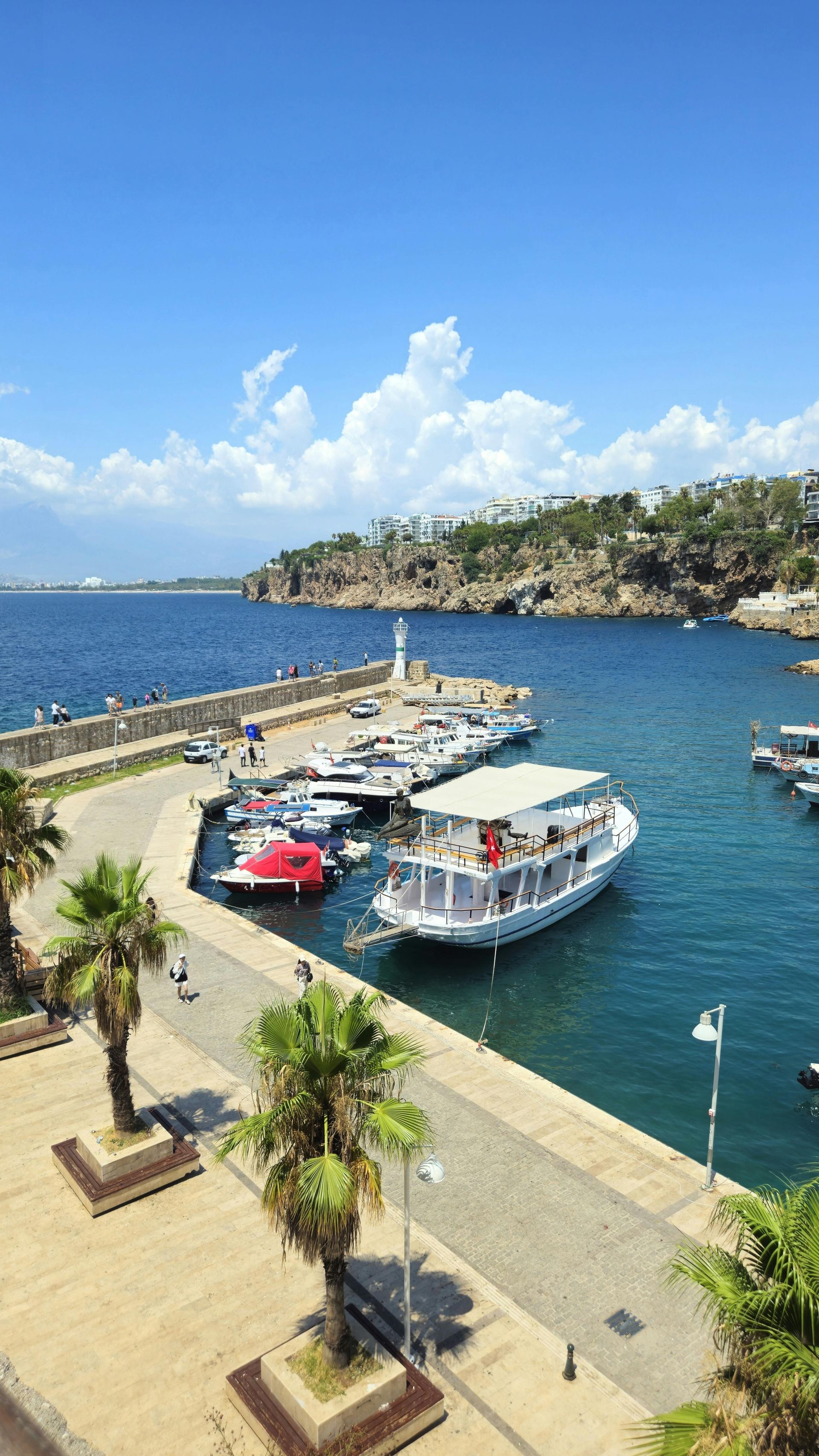 A boat is docked in a harbor next to a dock in the Mediterranean ocean. 