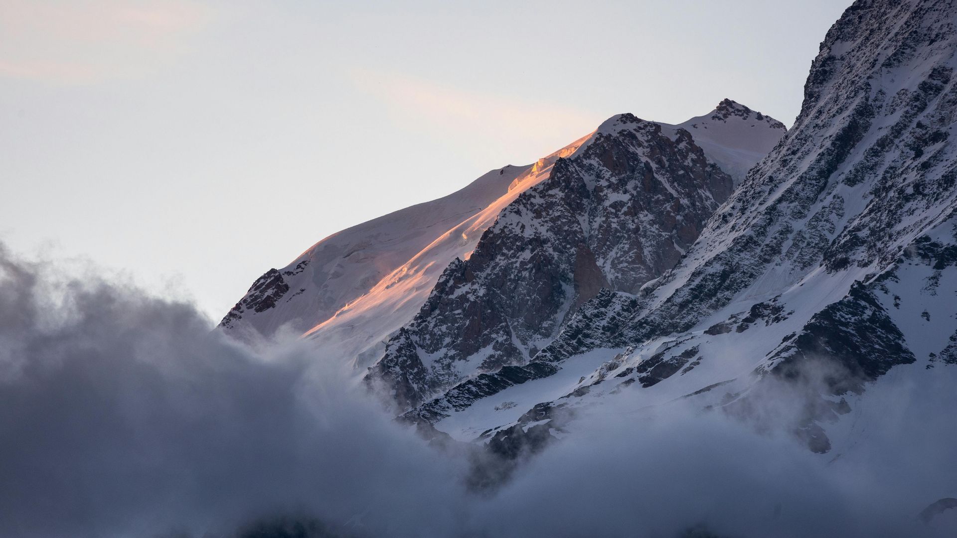 The sun is shining through the clouds on a snowy mountain in Chamonix, France.